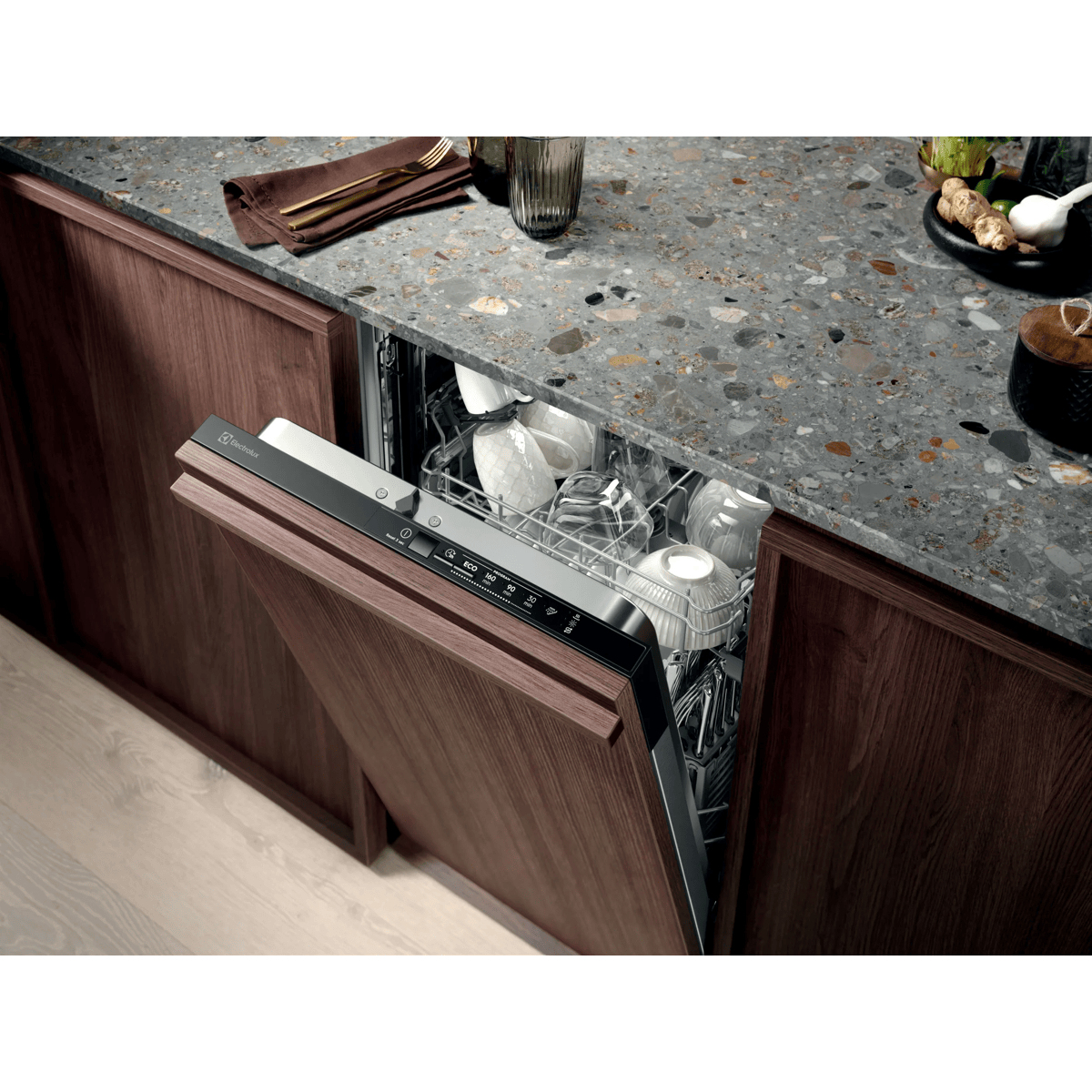 Lavastoviglie con pannello in legno aperta in cucina moderna con piano in marmo e bicchieri.