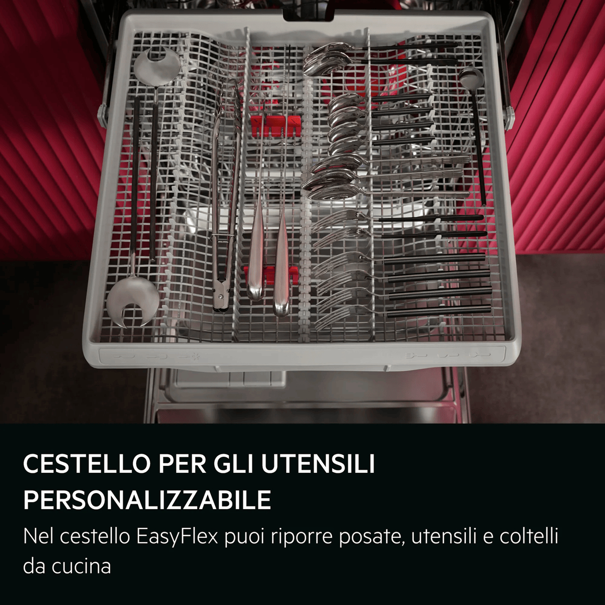 Un cassetto della lavastoviglie aperto con posate, cucchiai e forchette ordinati, su sfondo rosso.
