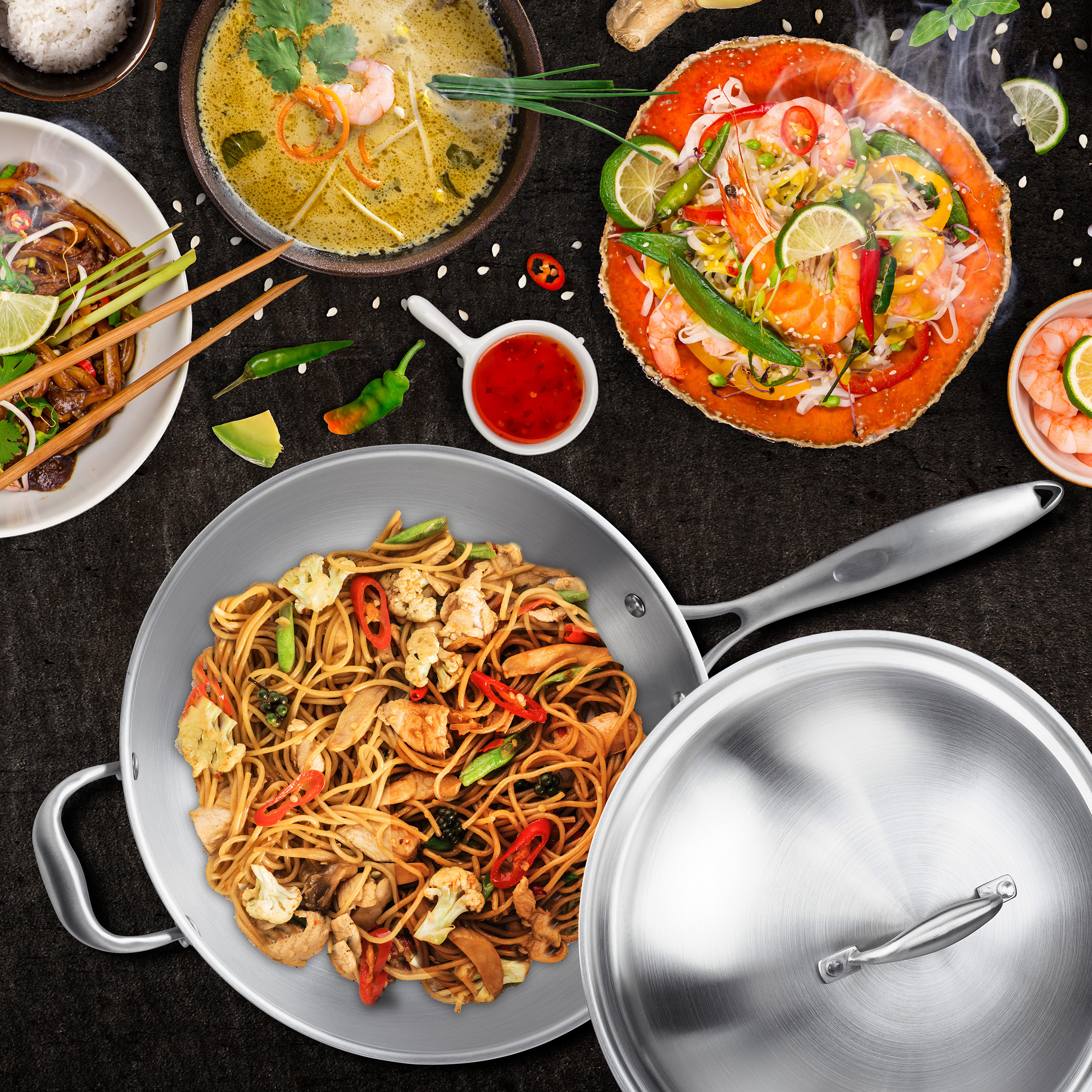Verschiedene asiatische Gerichte, darunter gebratene Nudeln in einer Pfanne, Suppe und Meeresfrüchte.
