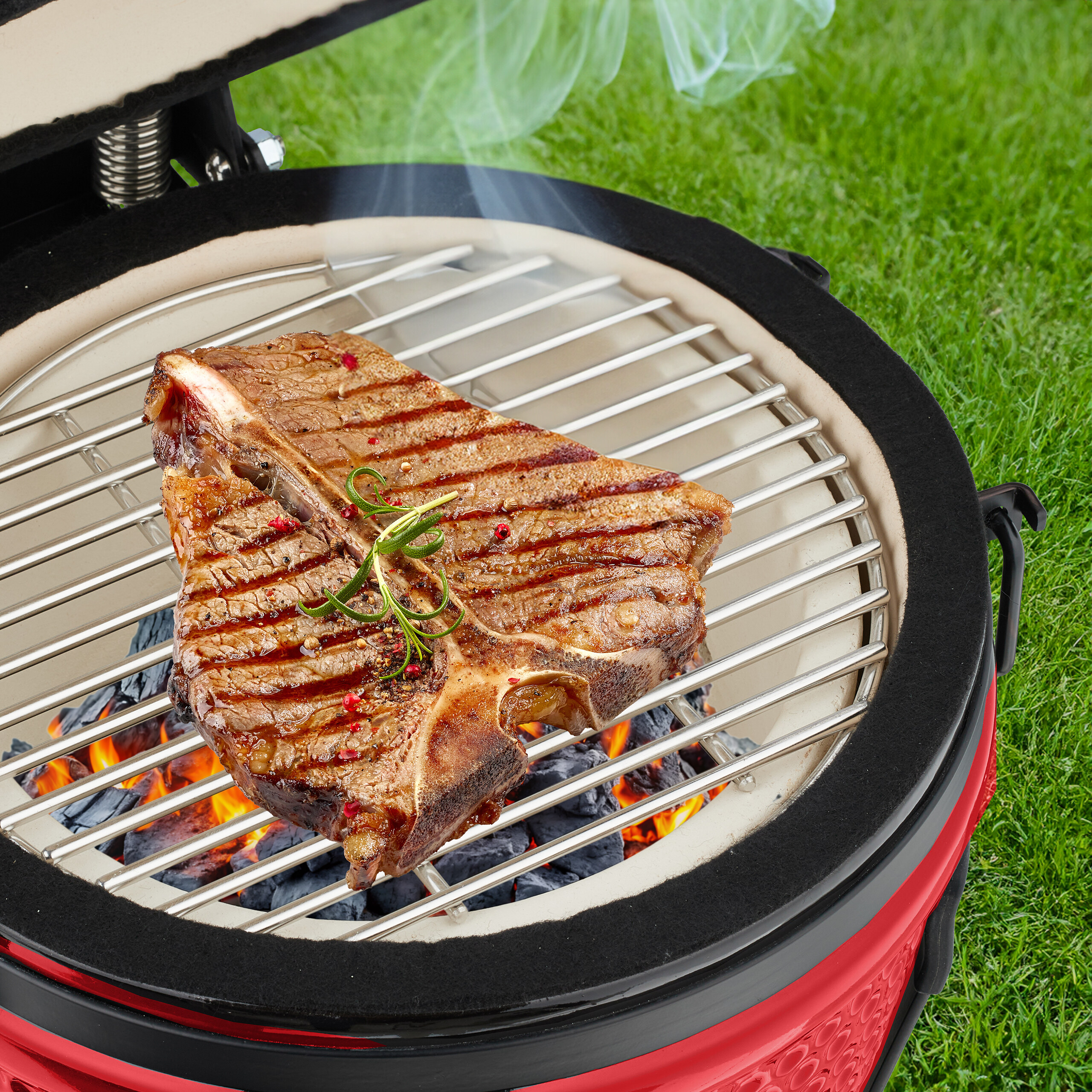 Ein T-Bone-Steak mit Grillstreifen und Kräutern brutzelt auf einem Holzkohlegrill über Glut, Rauch steigt auf.
