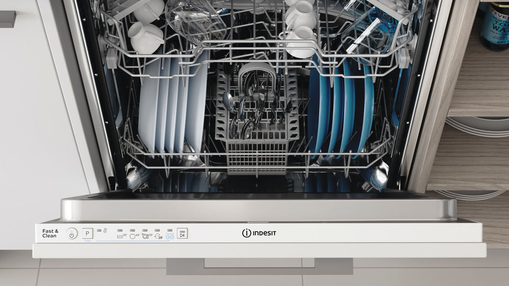 Una lavastoviglie Indesit aperta con piatti, tazze e posate nei cestelli.