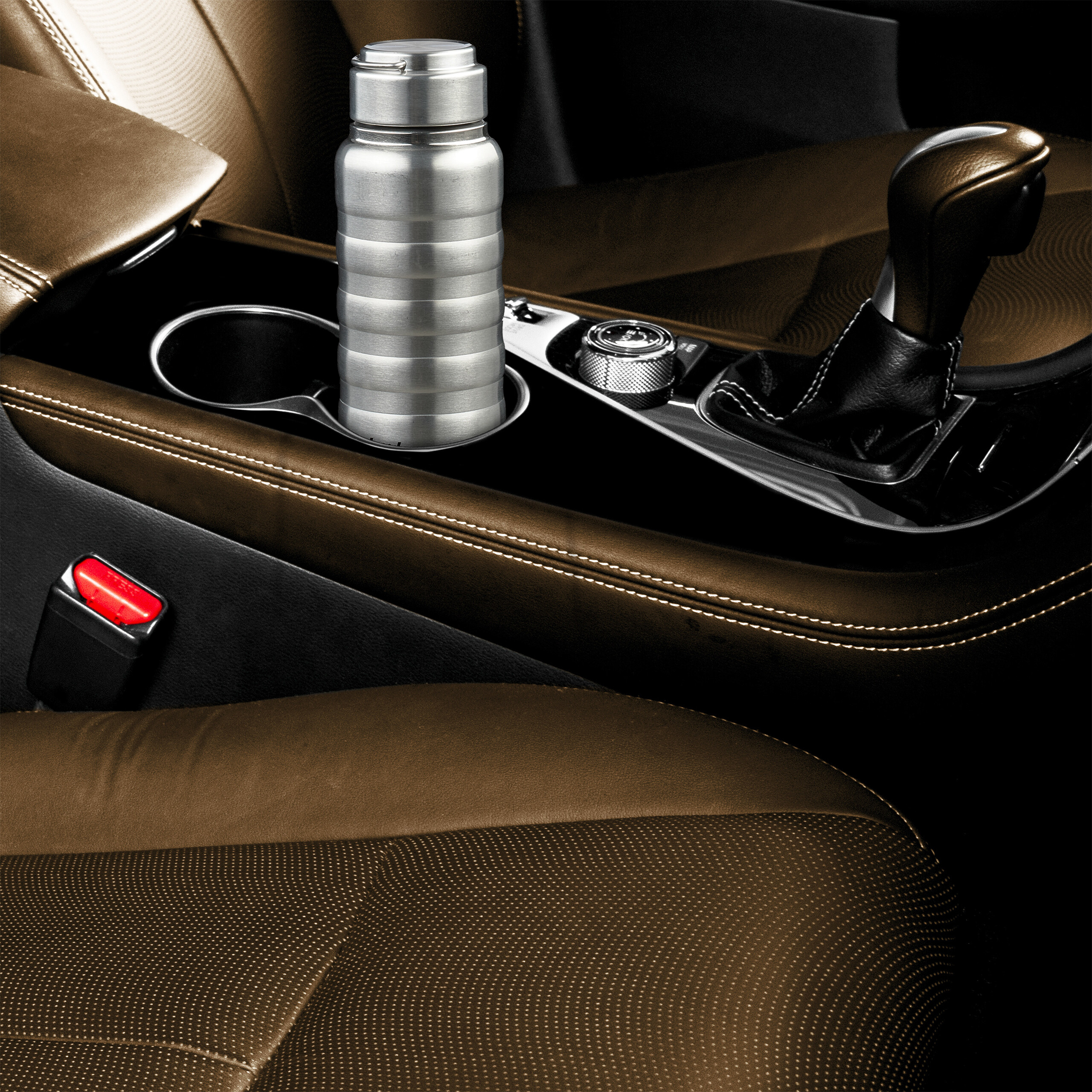 Eine Edelstahl-Thermoskanne in einem Getränkehalter der braunen Lederausstattung eines Autos.