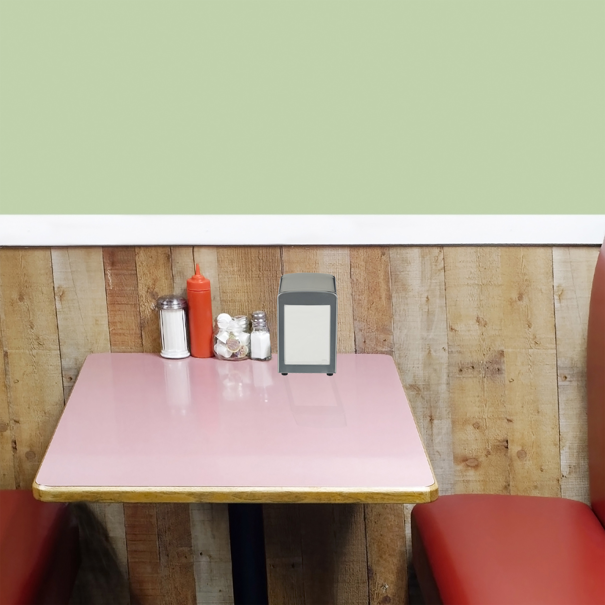 Ein rosafarbener Tisch in einem Diner mit rotem Sitz, Holzwand und Serviettenhalter.