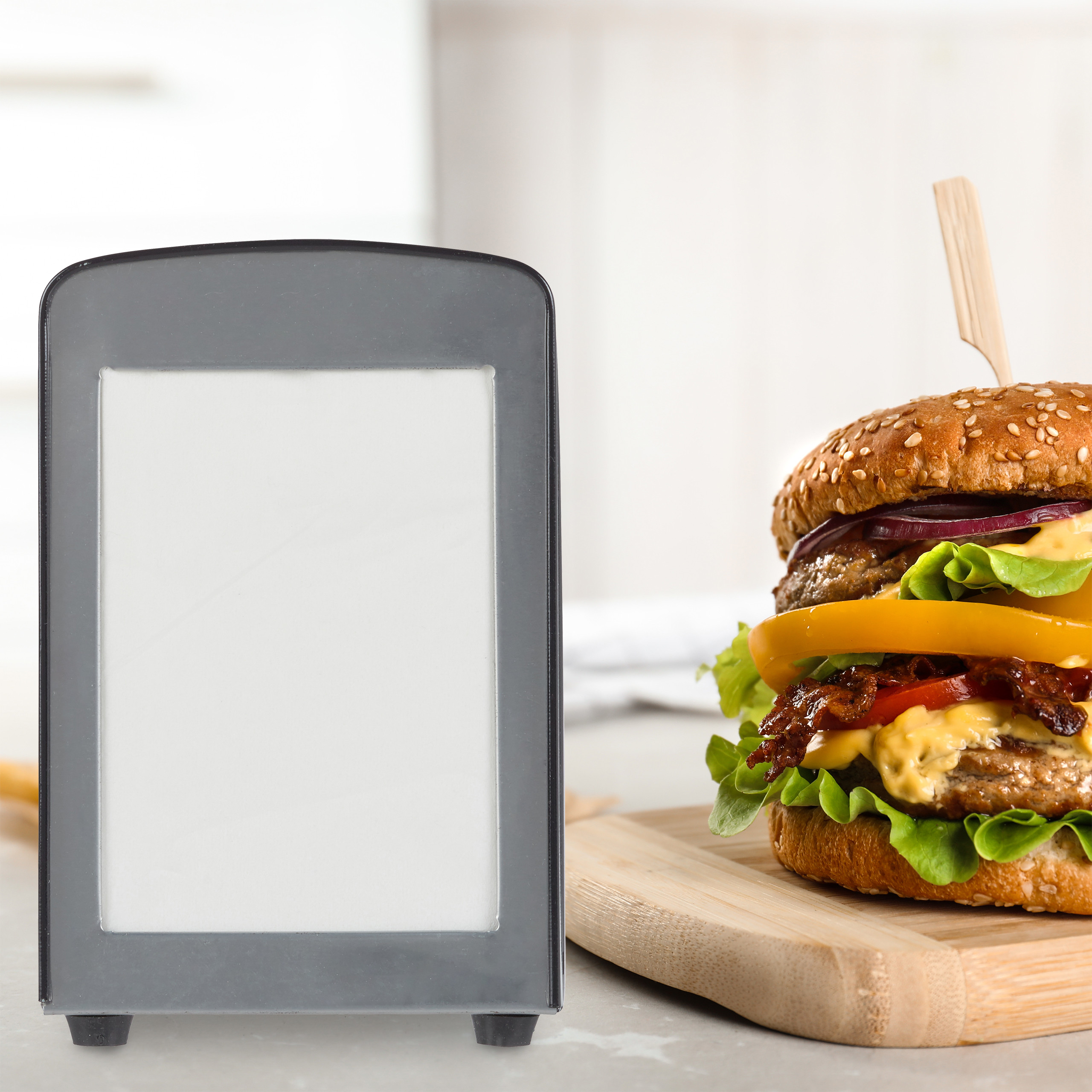 Ein leckerer Burger auf einem Holzbrett neben einem leeren Werbeschild auf einem Tisch.