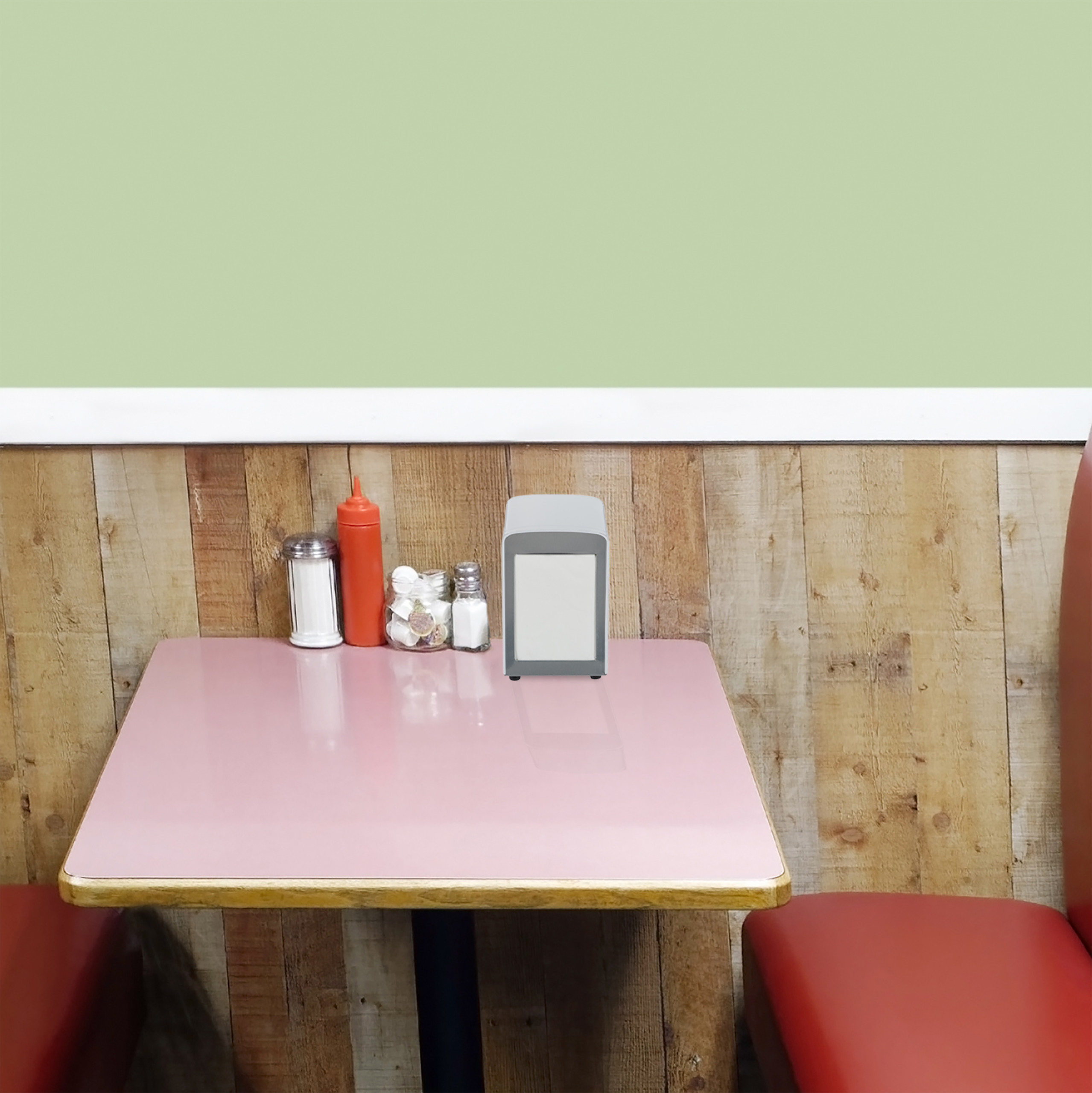 Ein rosafarbener Tisch in einem Diner mit rotem Sitz, Holzwand und grüner Decke.