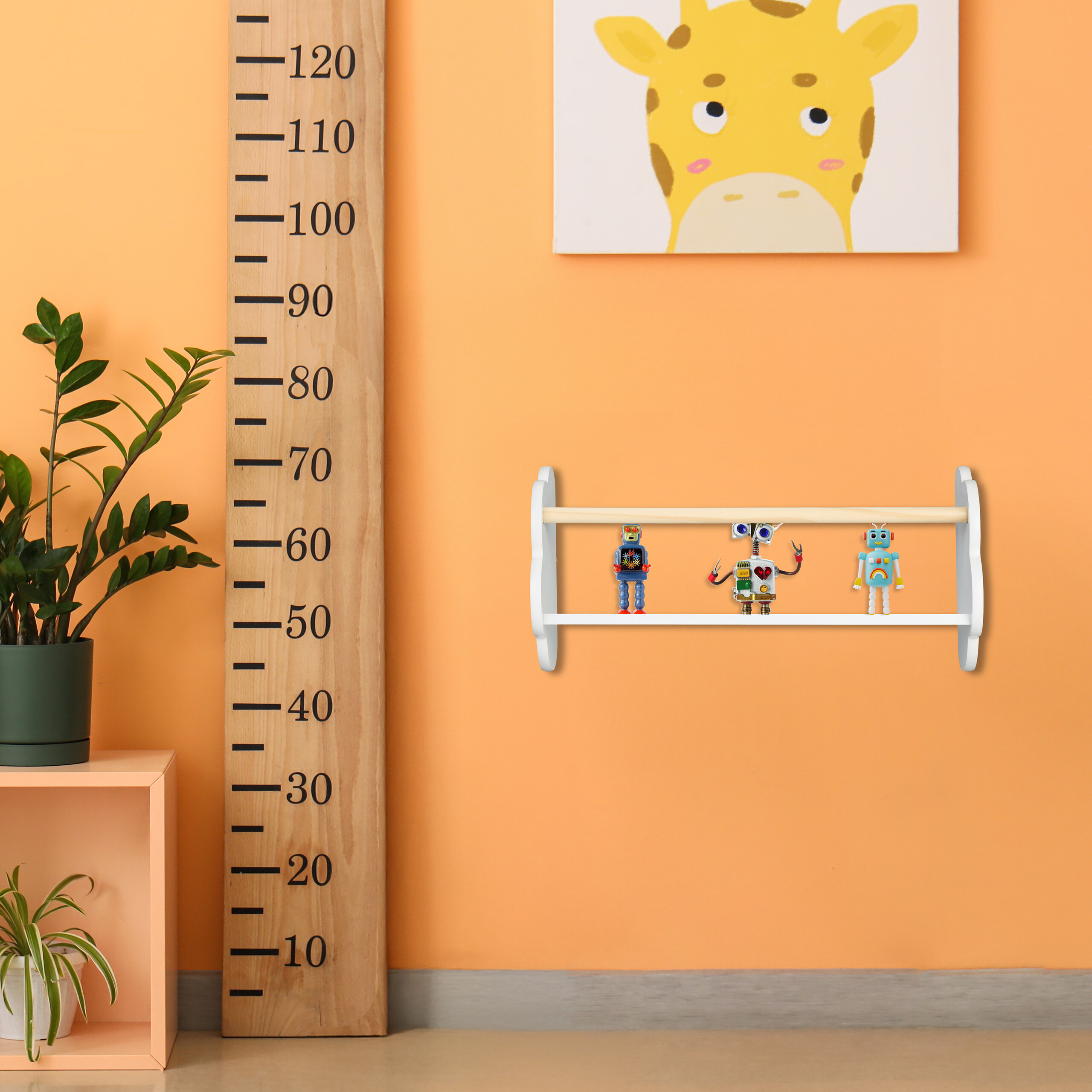 Eine orange Wand mit Messlatte, Giraffenbild, einem kleinen Regal mit drei Spielzeugrobotern und einer Topfpflanze.