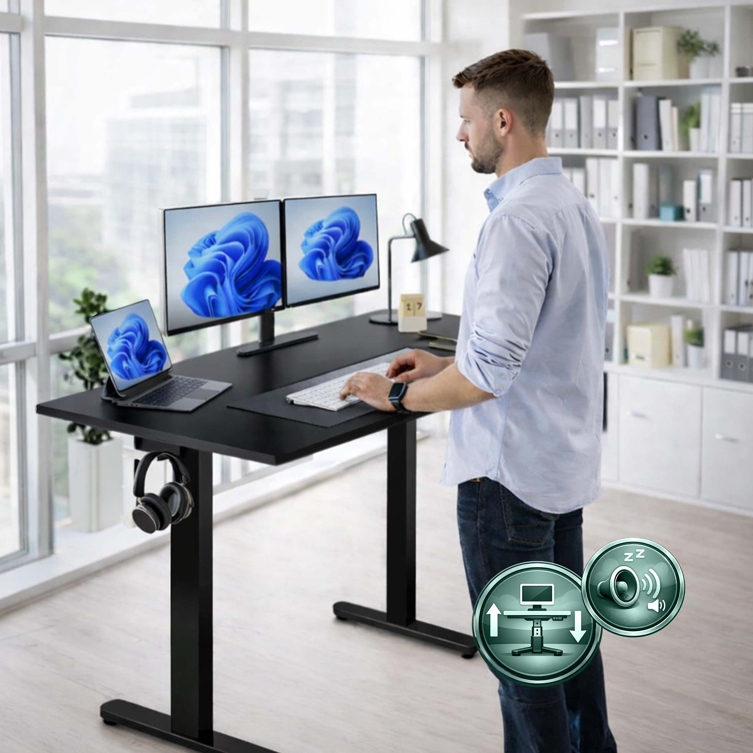 Ein Mann steht an einem schwarzen höhenverstellbaren Schreibtisch mit zwei Monitoren in einem hellen Büro.