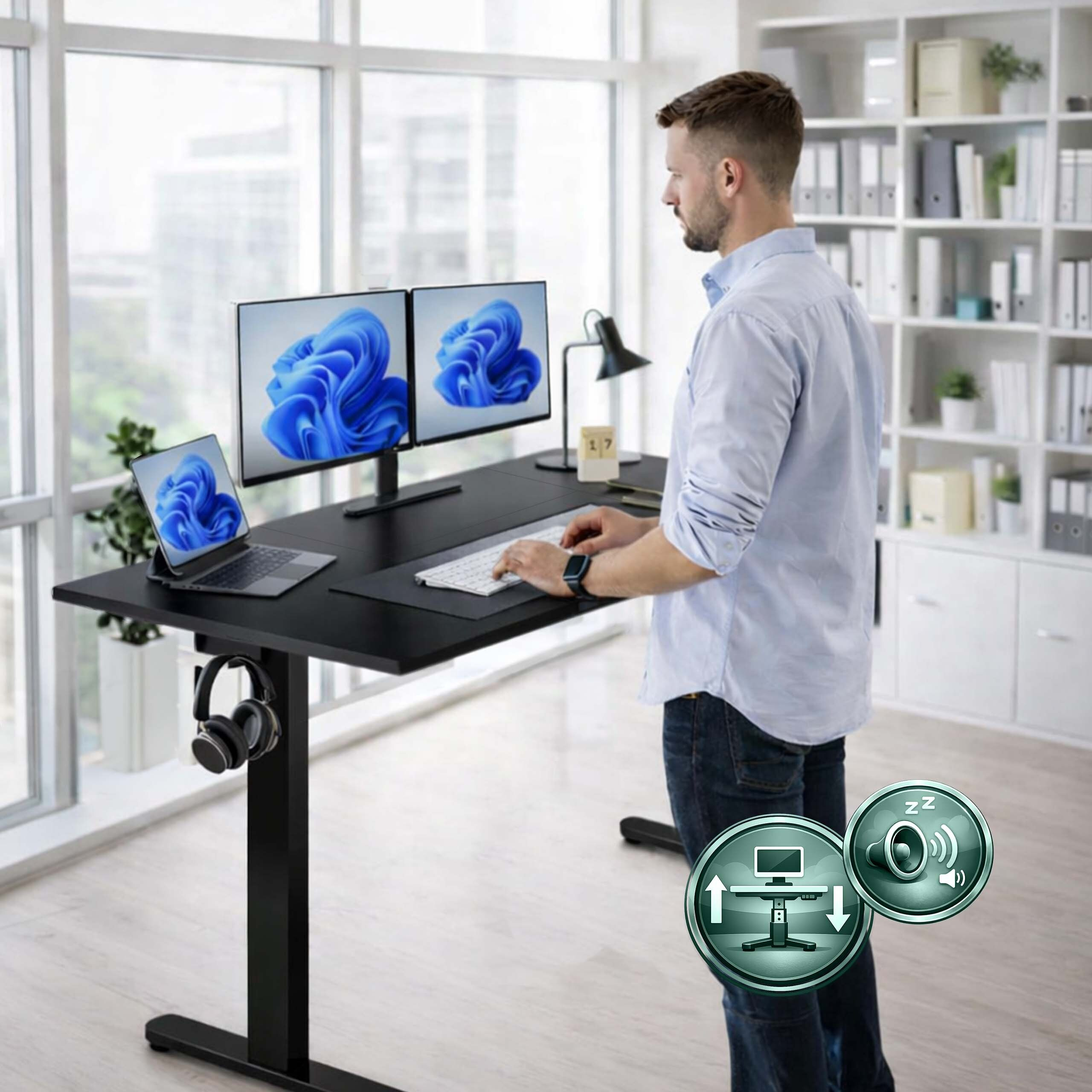 Mann arbeitet im Stehen an einem verstellbaren Schreibtisch mit zwei Monitoren, Laptop und hellen Fenstern im Hintergrund.
