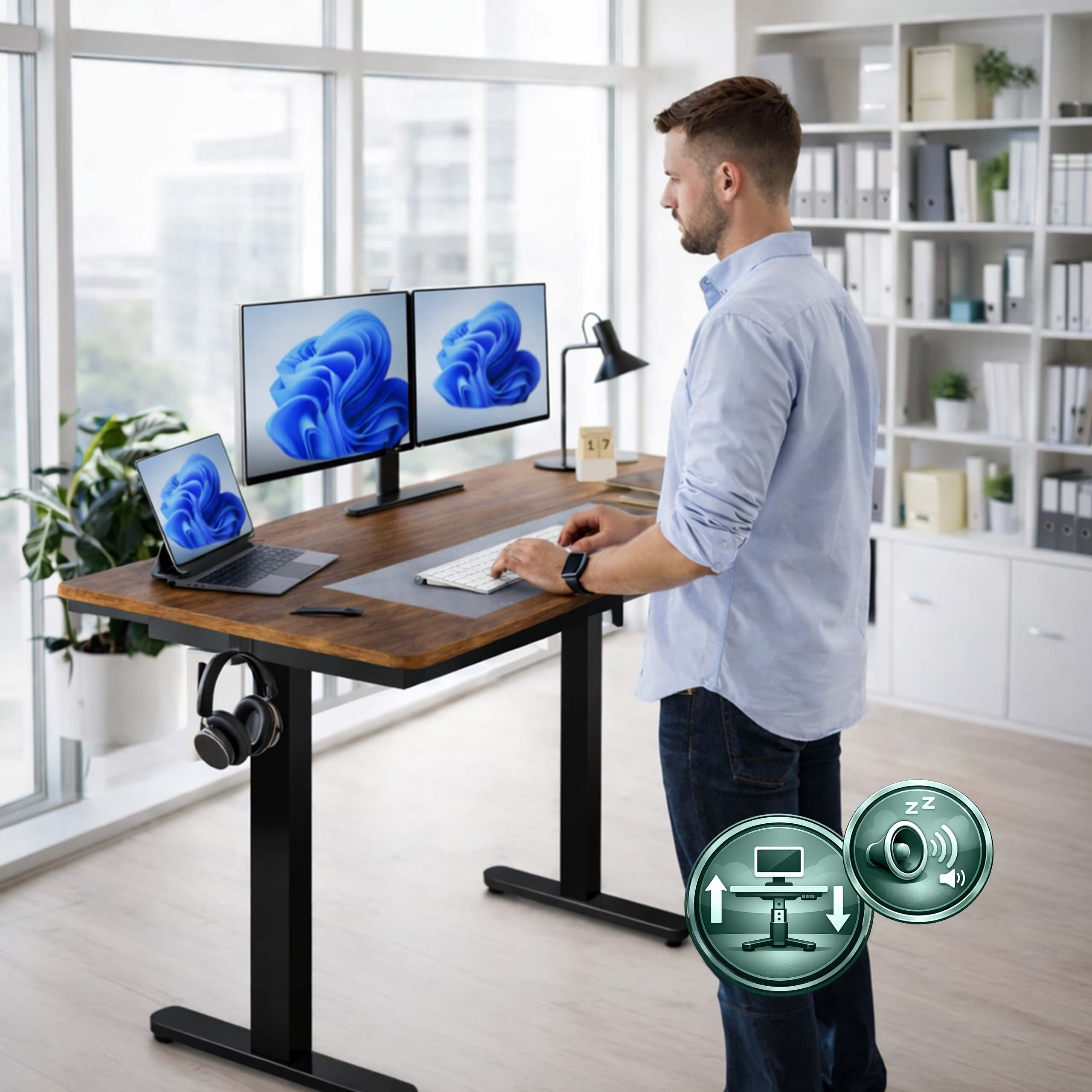 Ein Mann steht an einem höhenverstellbaren Schreibtisch und tippt auf einer Tastatur vor zwei Monitoren.