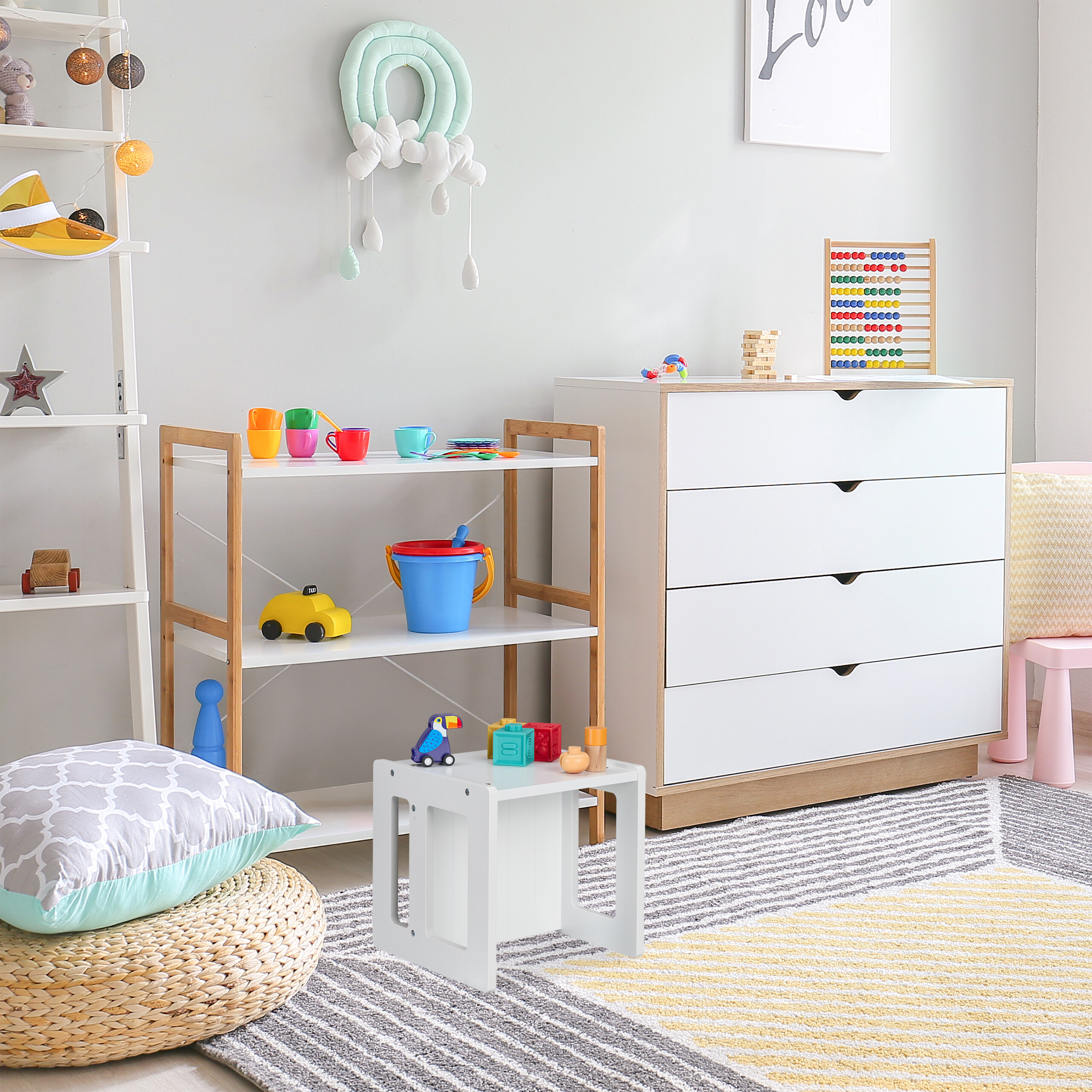 Ein helles Kinderzimmer mit Regal, Kommode, Spielzeug und einem gemusterten Teppich auf dem Boden.