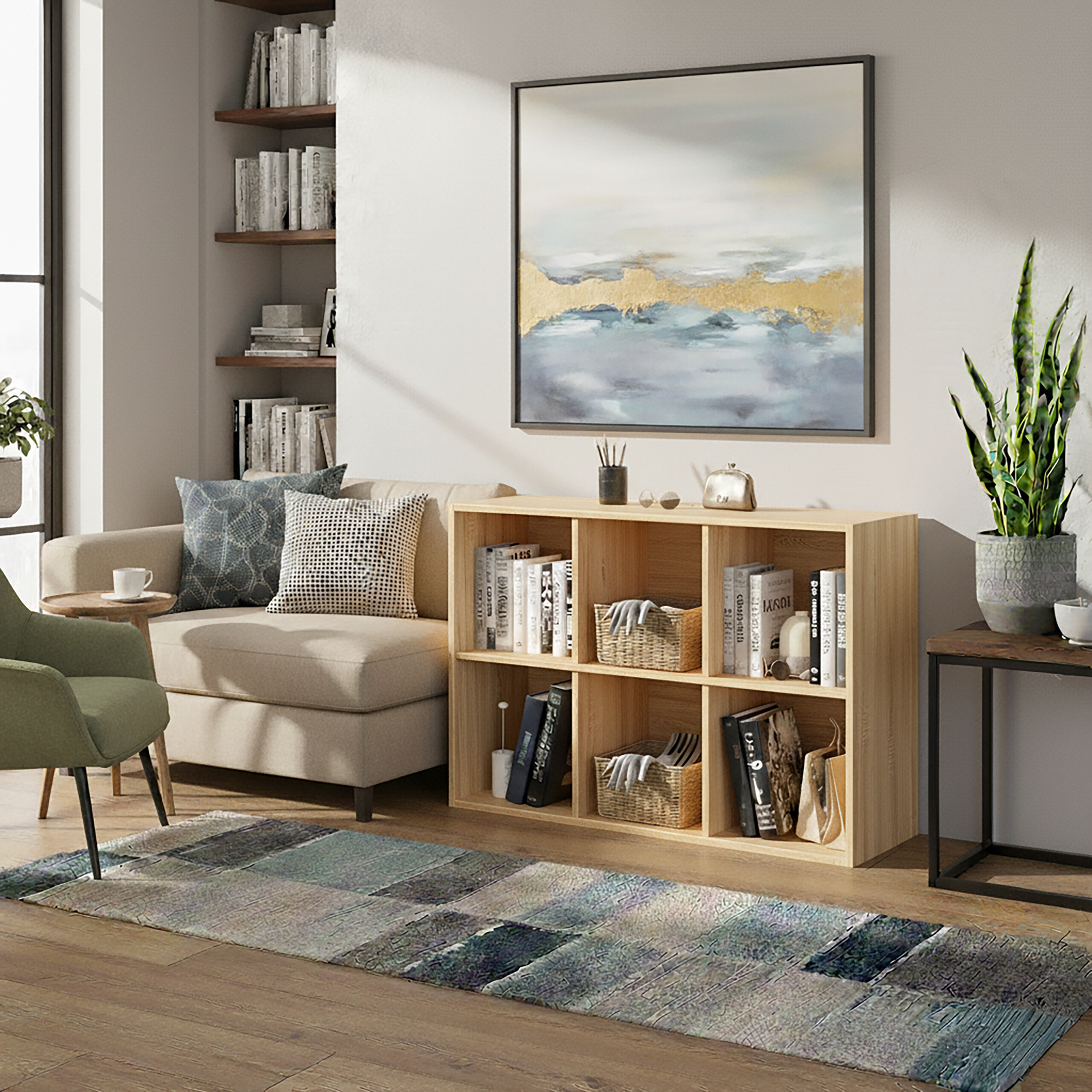 Ein helles Wohnzimmer mit Regal, Sofa, grünem Sessel, großer Wandkunst und einem gemusterten Teppich auf Holzfußboden.