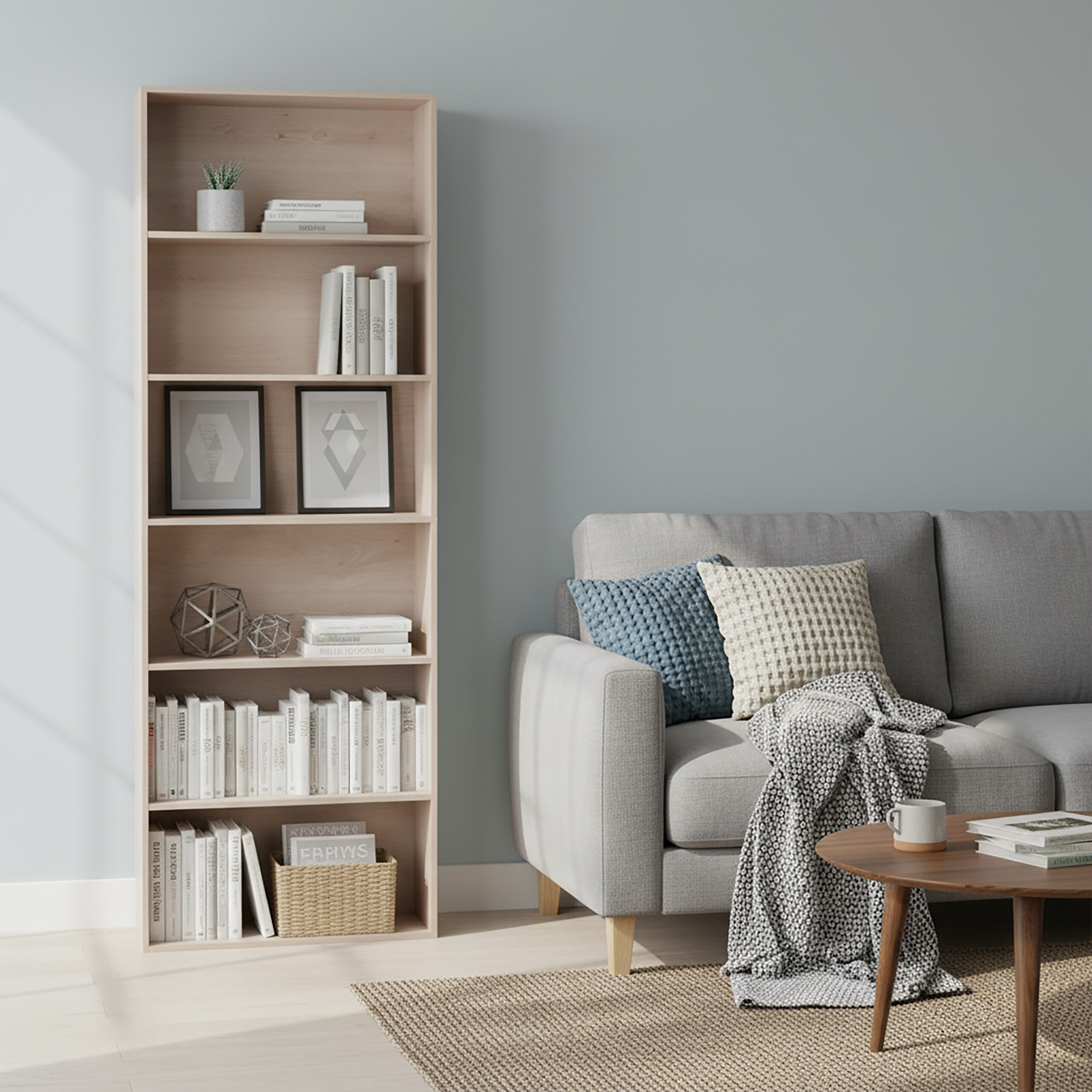 Wohnzimmer mit grauer Couch, Holzbücherregal, Kissen, Decke, Teppich und Holztisch vor blauer Wand.
