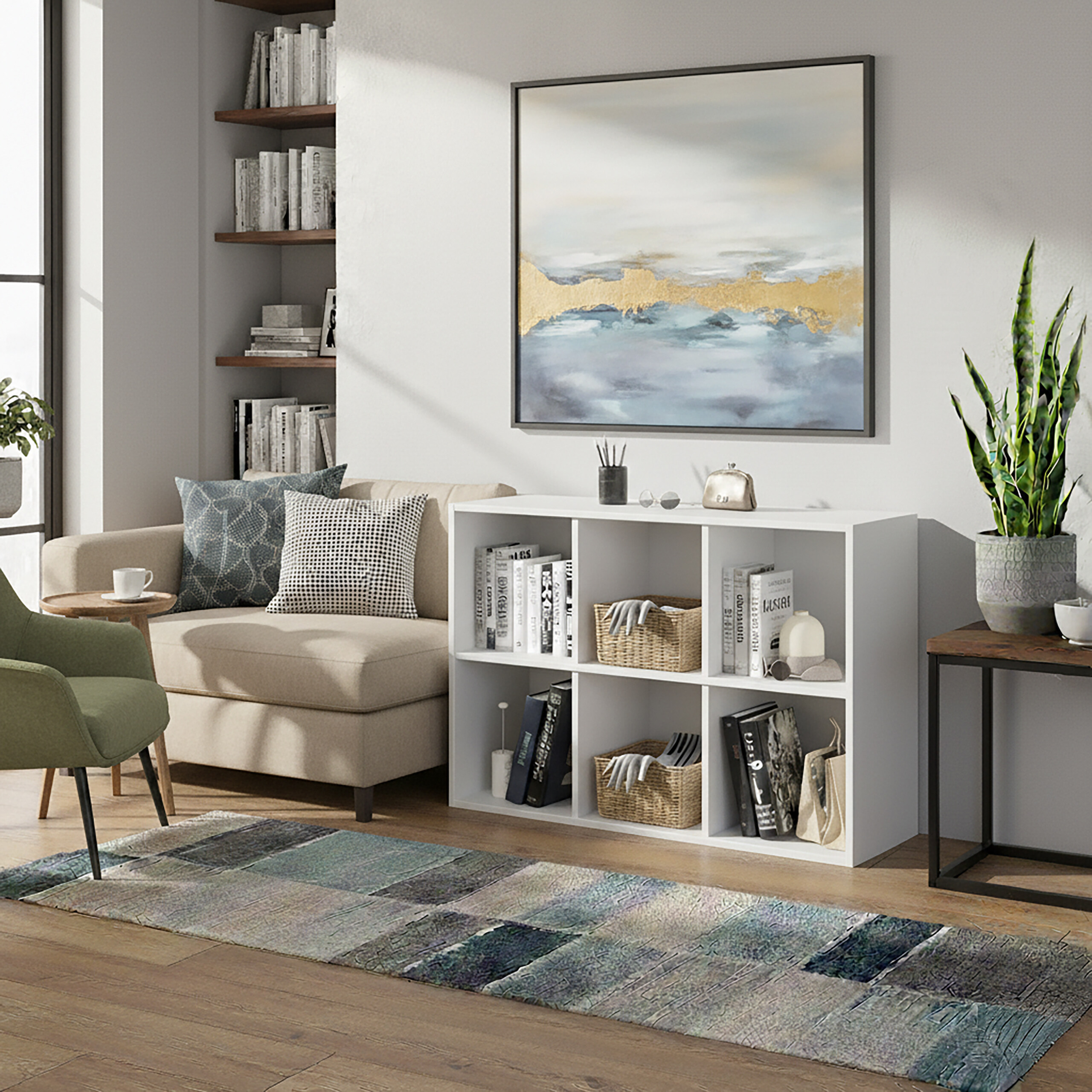 Ein modernes Wohnzimmer mit einem weißen Regal, beigem Sofa, grünem Sessel und abstrakter Wandkunst.