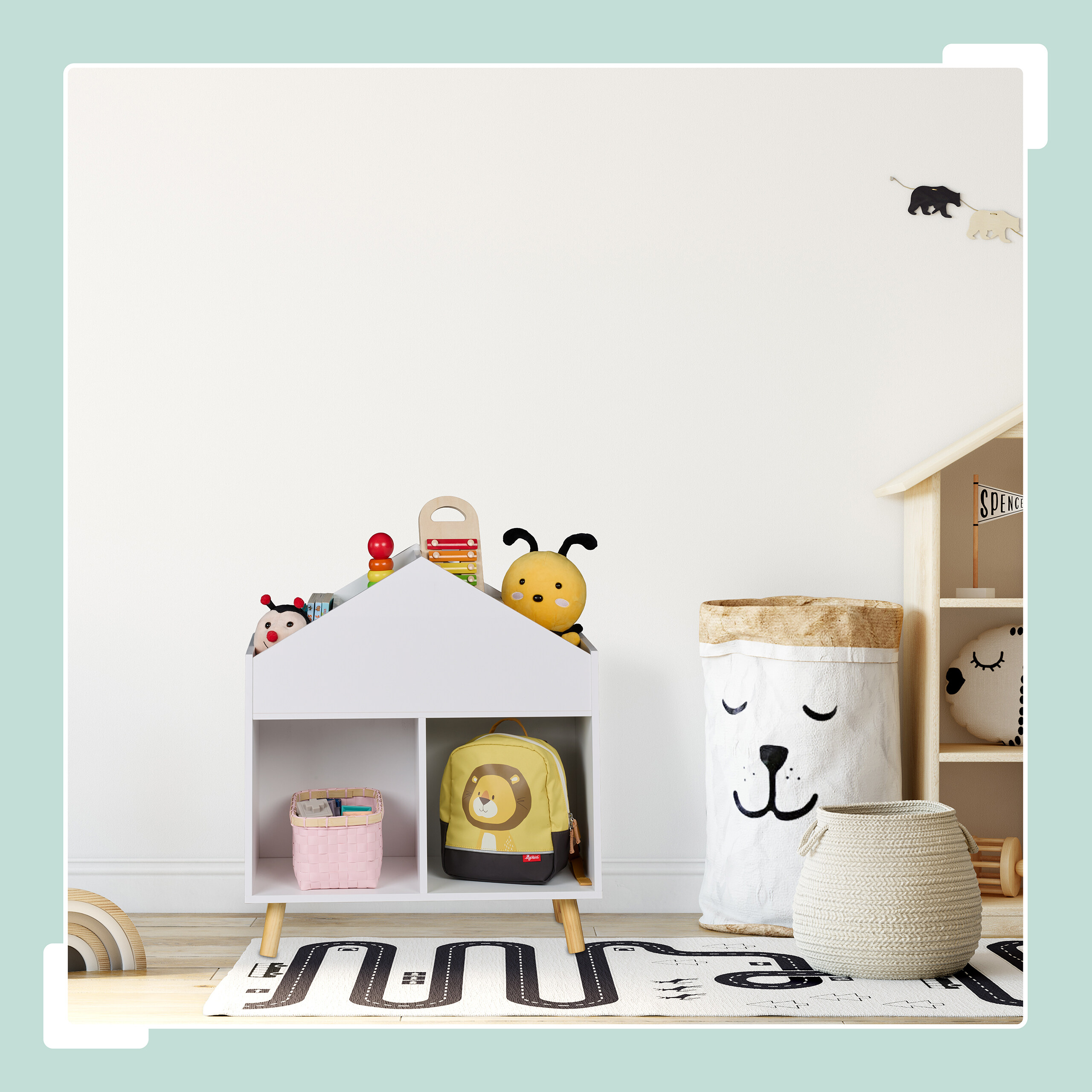 Ein Kinderzimmer mit einem weißen Hausregal, Spielzeug, einem Aufbewahrungsbeutel und einem Spielteppich.