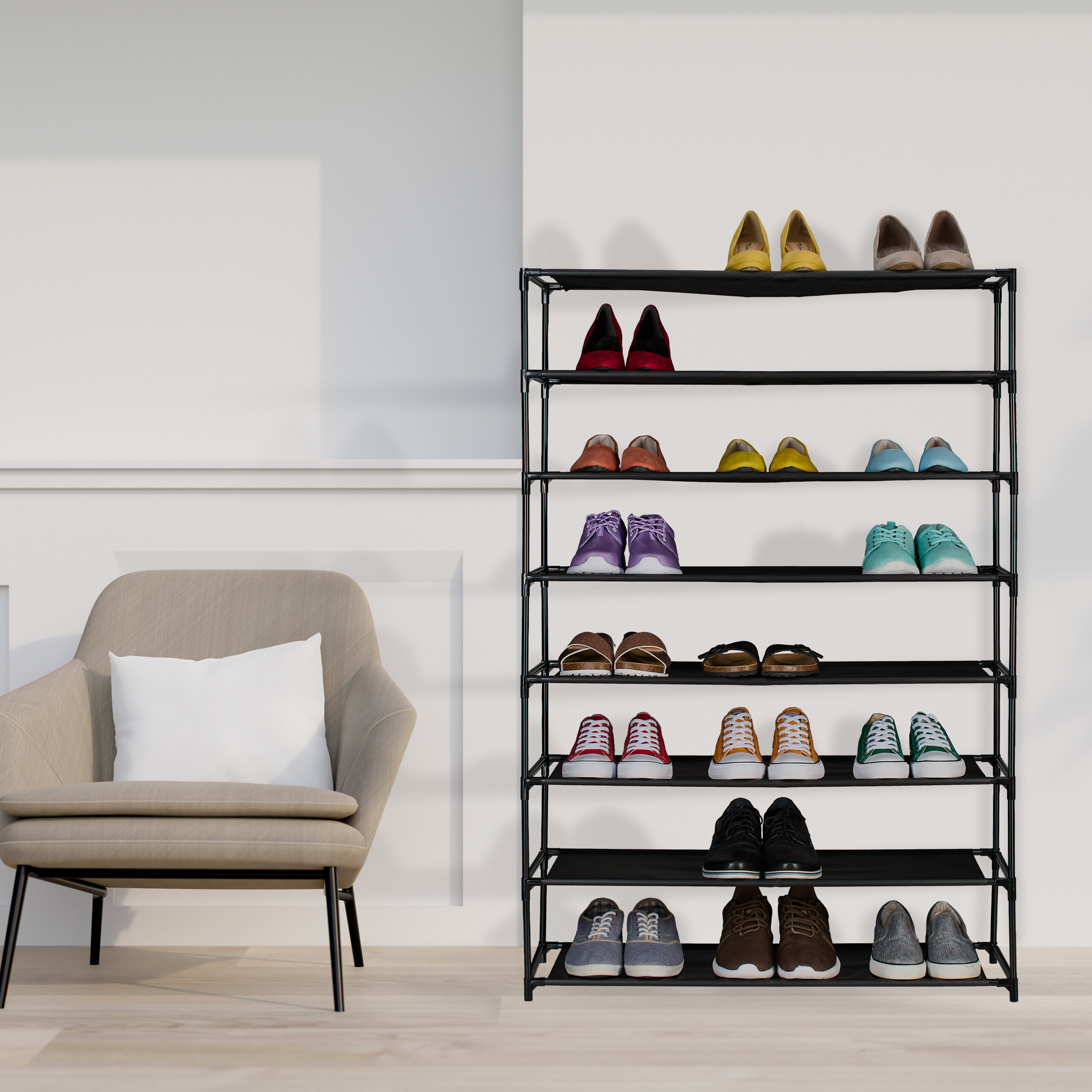Ein großes, schwarzes Schuhregal voll mit bunten Schuhen steht neben einem beigefarbenen Sessel.