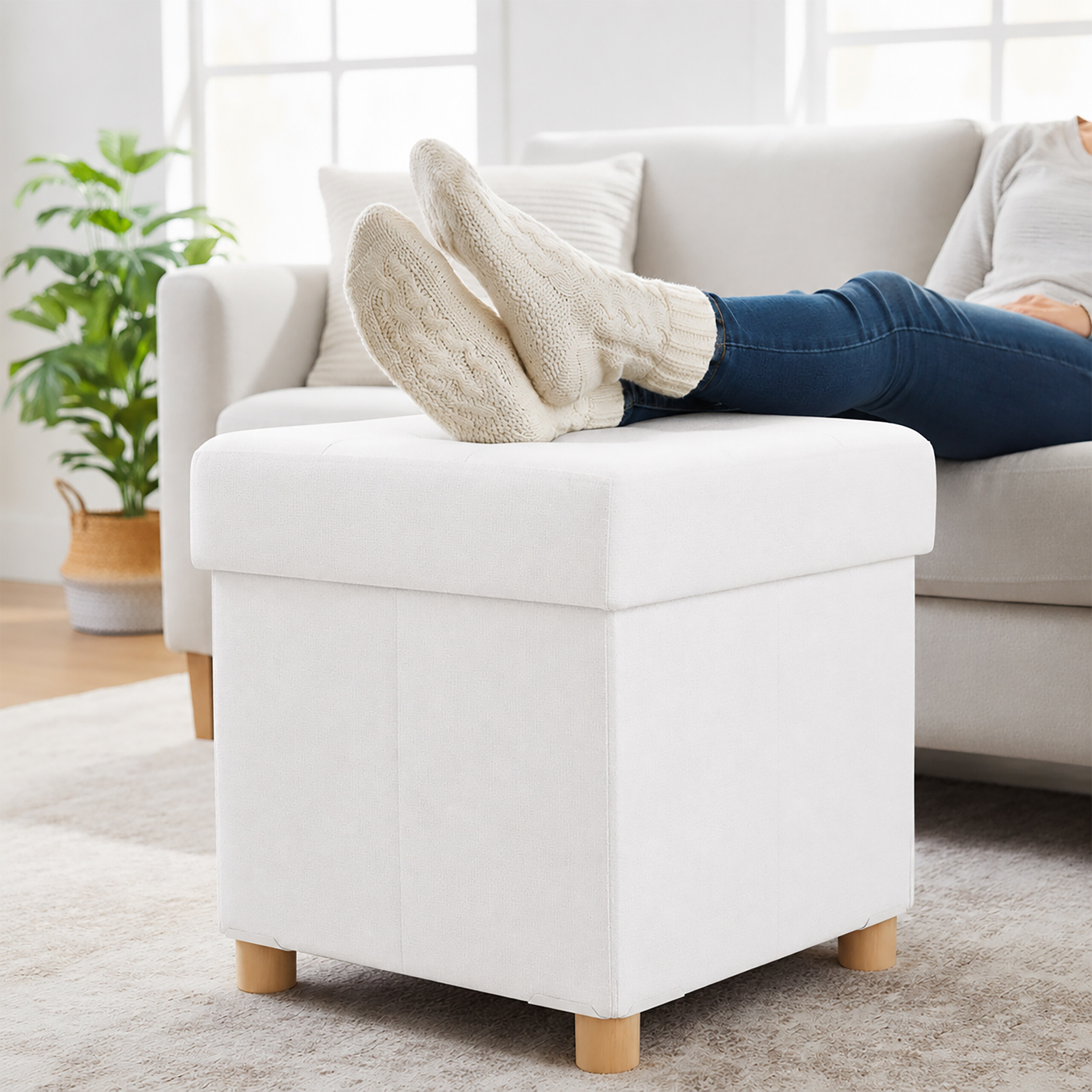 Person entspannt auf einer Couch mit den Füßen auf einem weißen gepolsterten Hocker.