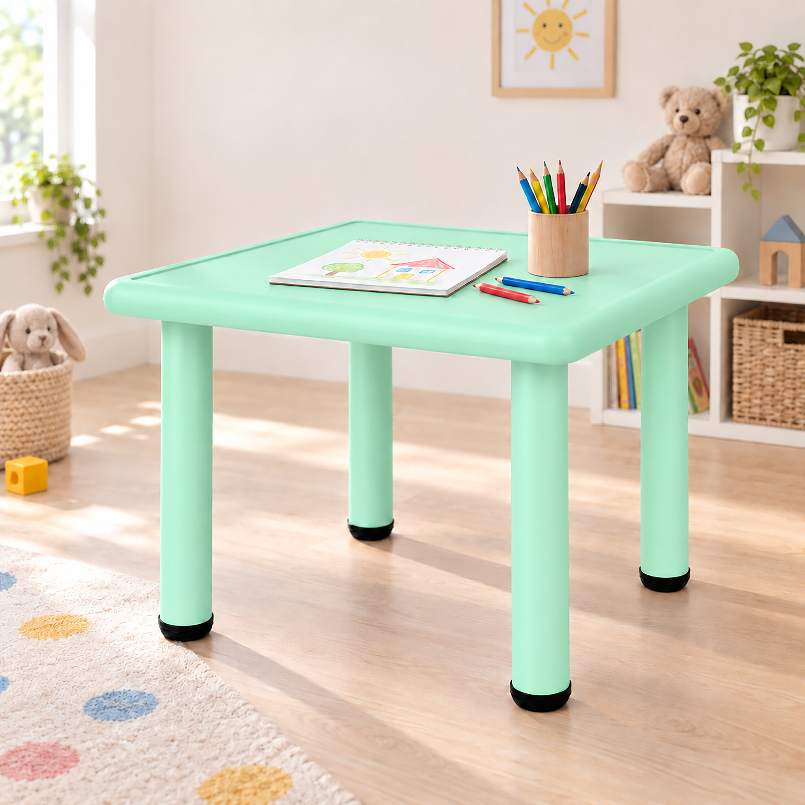 Ein mintgrüner Kindertisch mit einem Skizzenbuch, Buntstiften und Spielzeug im Hintergrund.