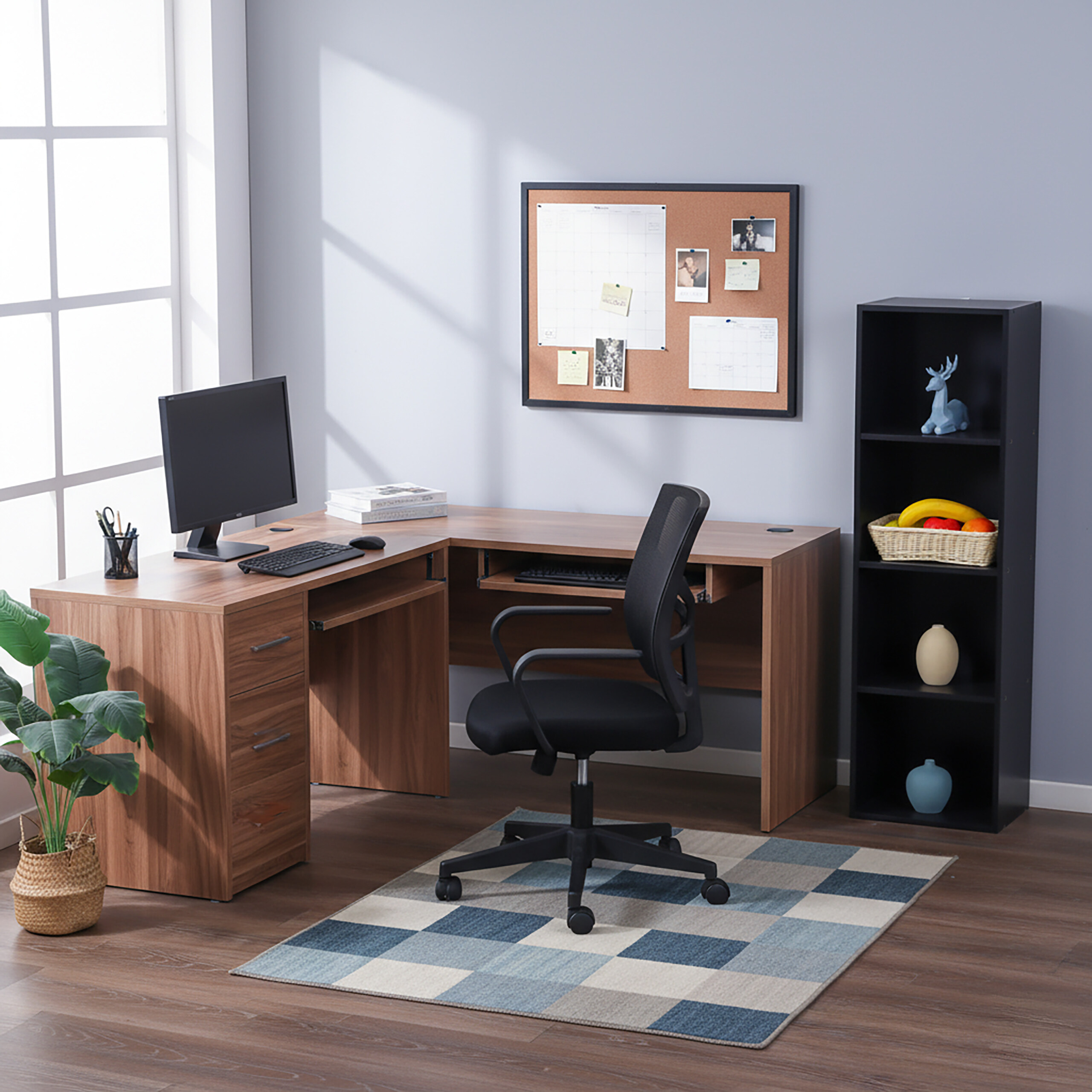 Ein L-förmiger Holztub mit Computer, schwarzem Stuhl, Pinnwand und hohem Regal in hellem Raum.