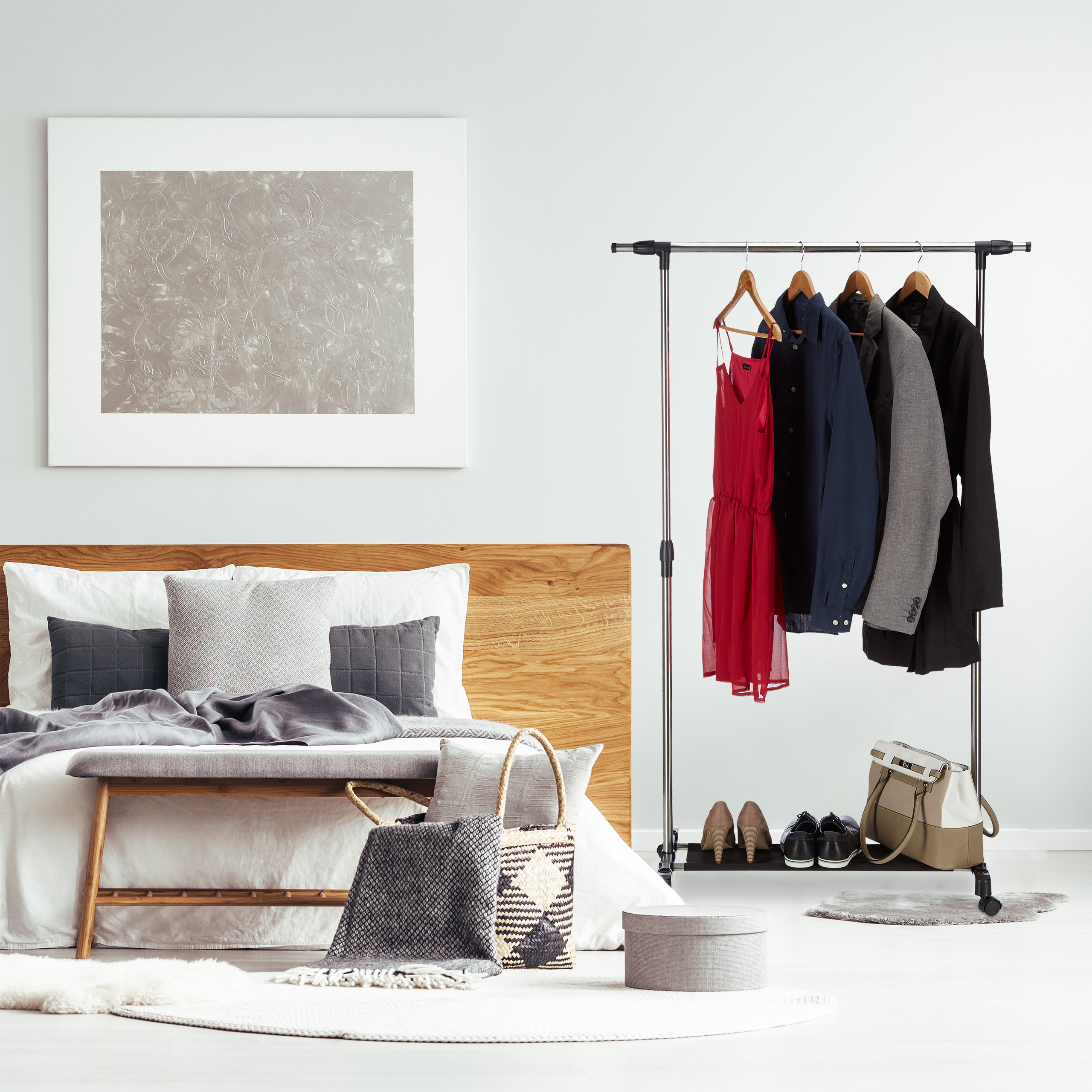 Moderne Schlafzimmereinrichtung mit Kleiderständer, Bett, abstraktem Wandbild und Korb.