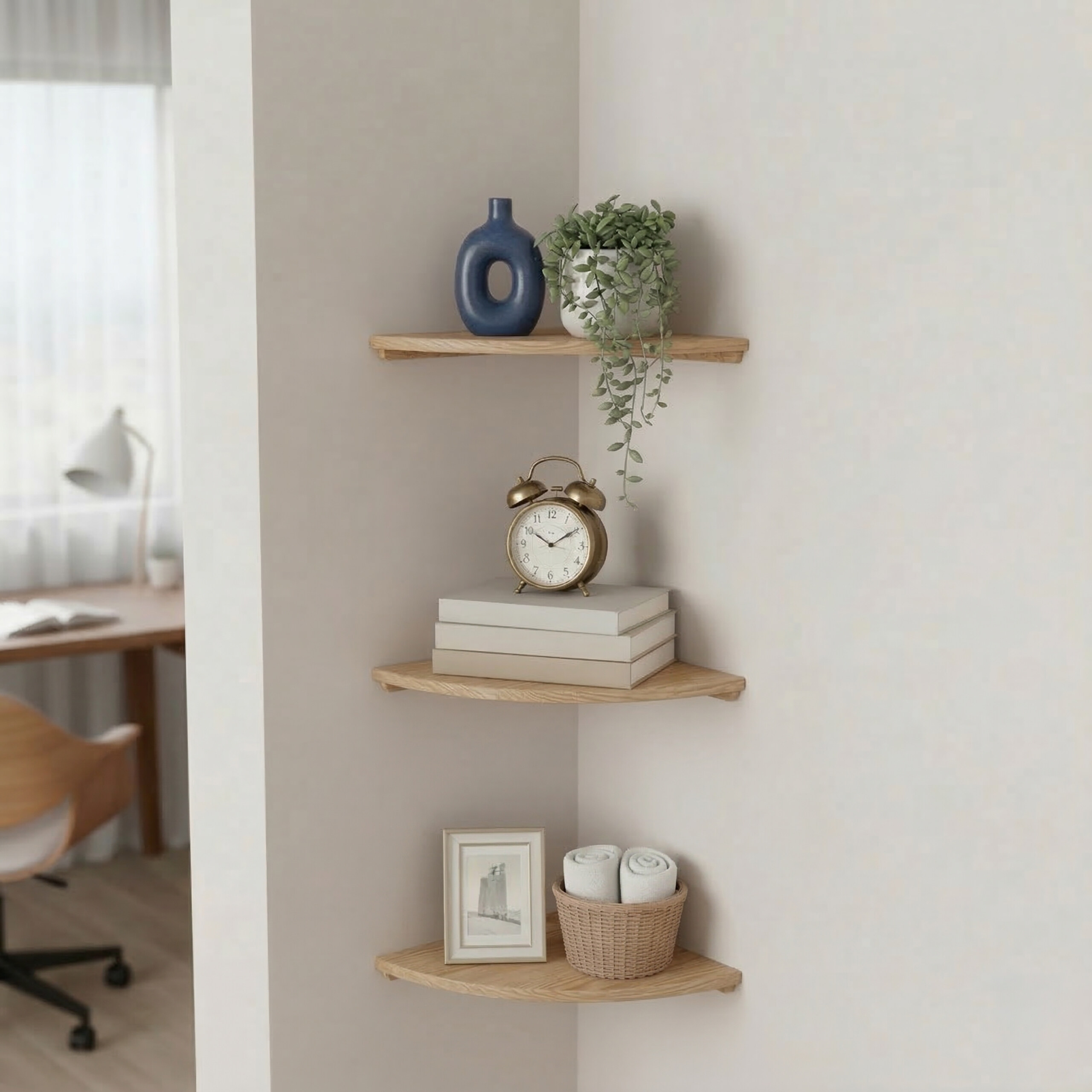 Drei hölzerne Eckregale an einer weißen Wand, dekoriert mit einer Vase, Pflanzen, einer Uhr, Büchern, einem Bild und Handtüchern.