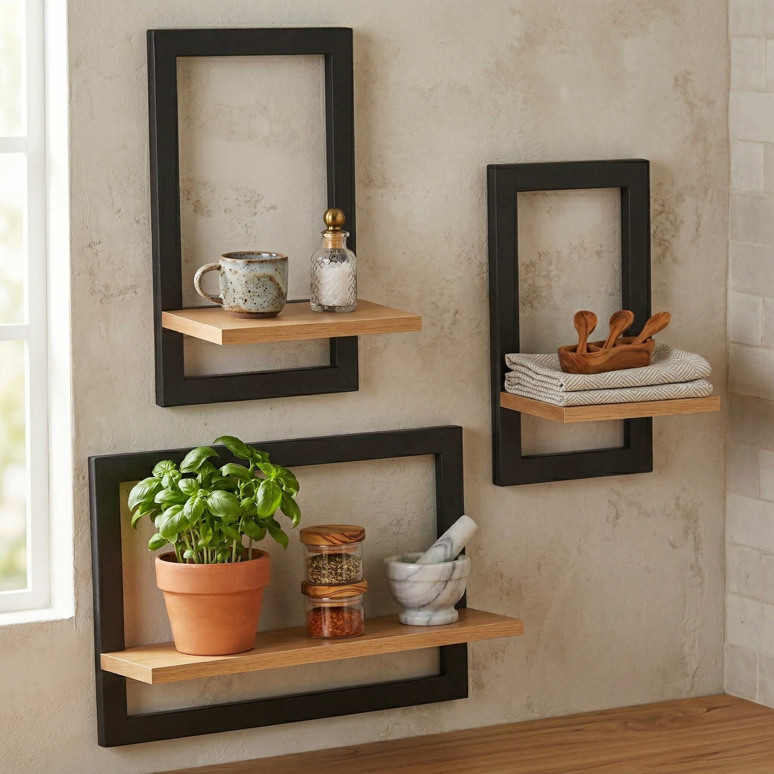 Drei schwarze Wandregale mit Holzbohlen an einer hellen Wand, bestückt mit Topfpflanze, Gewürzen und Utensilien.