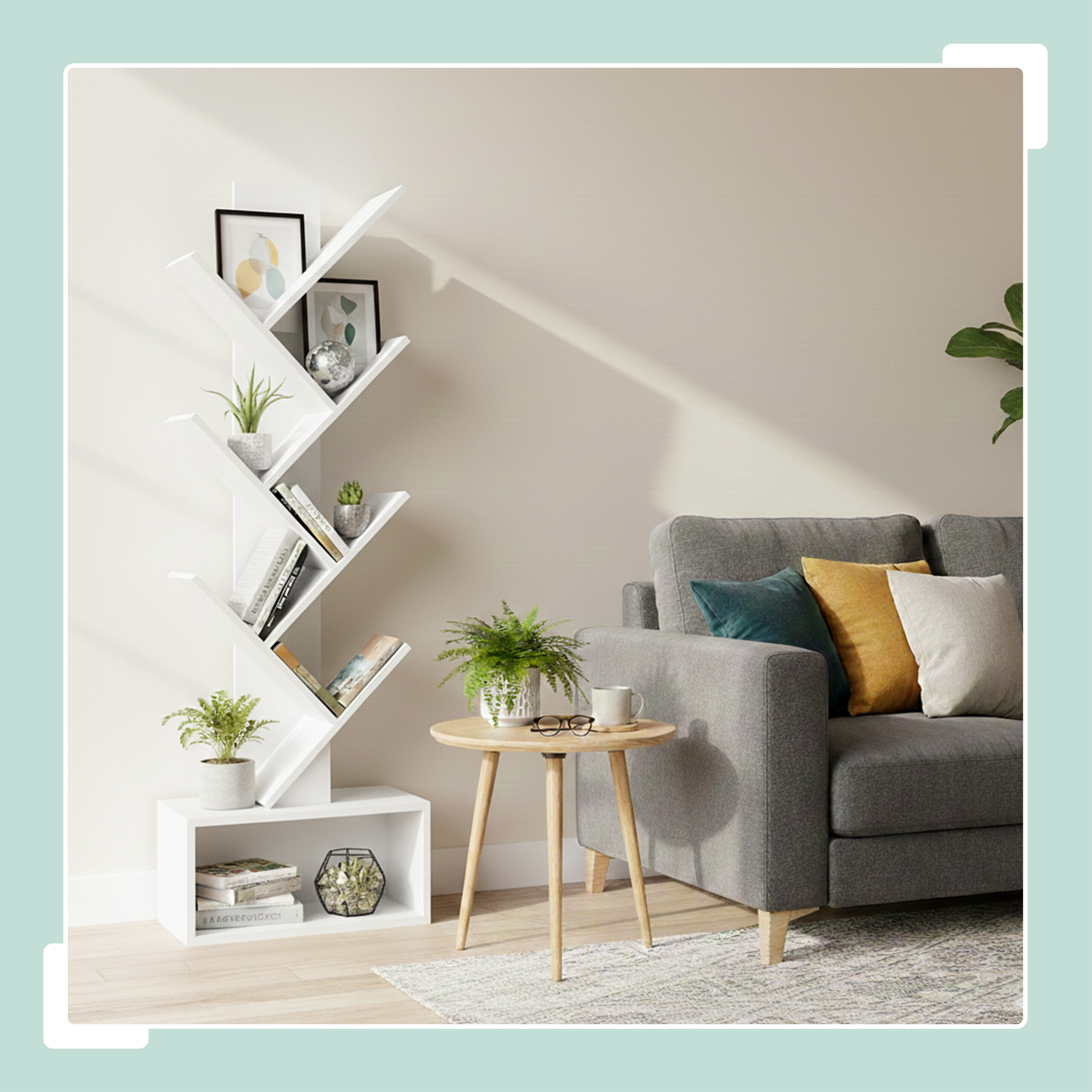 Ein weißes baumförmiges Regal mit Büchern, Pflanzen und Dekoration steht neben einem grauen Sofa mit farbigen Kissen.
