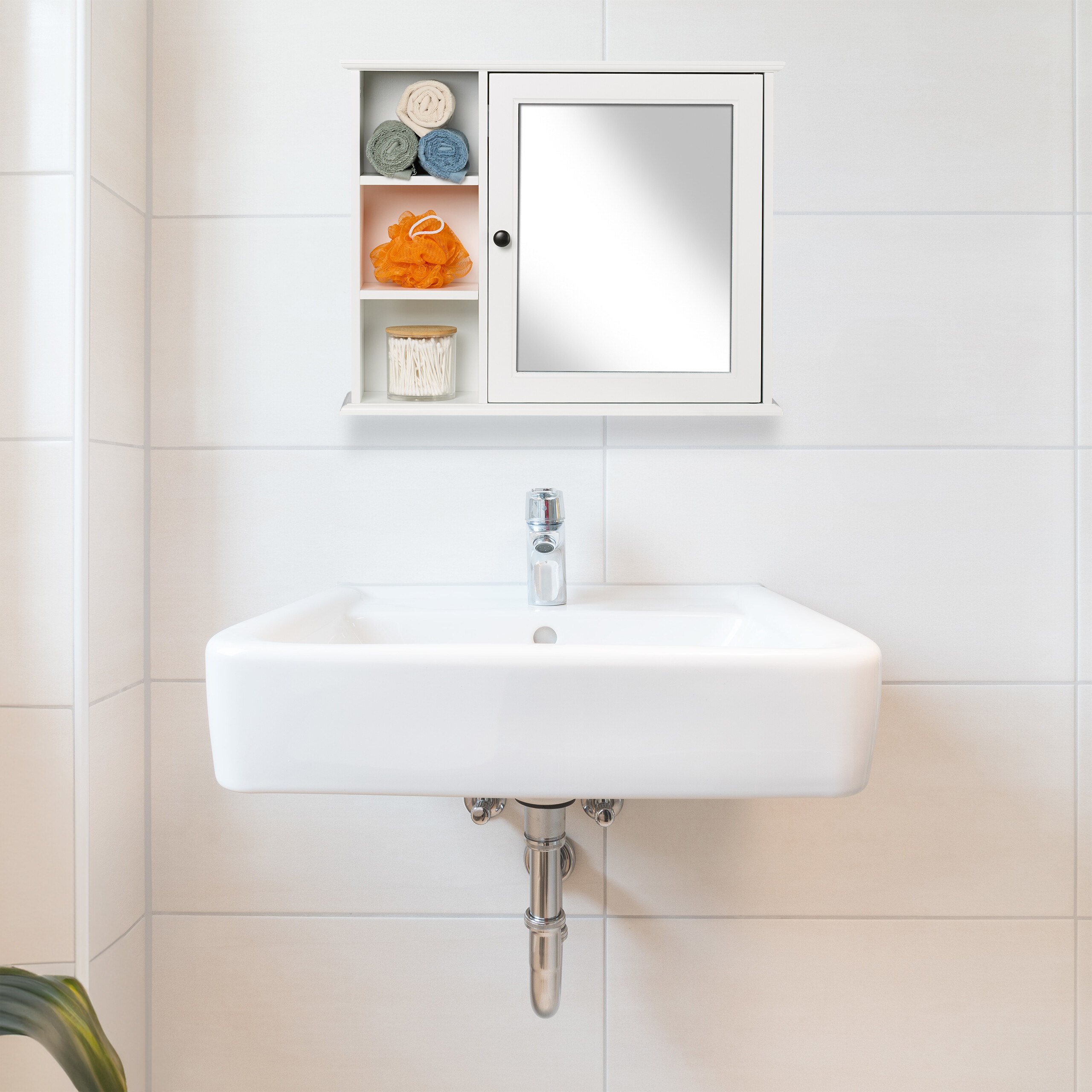 Ein weißes Waschbecken mit Chromarmatur vor hellen Fliesen, darüber ein weißer Spiegelschrank mit offenen Regalen.