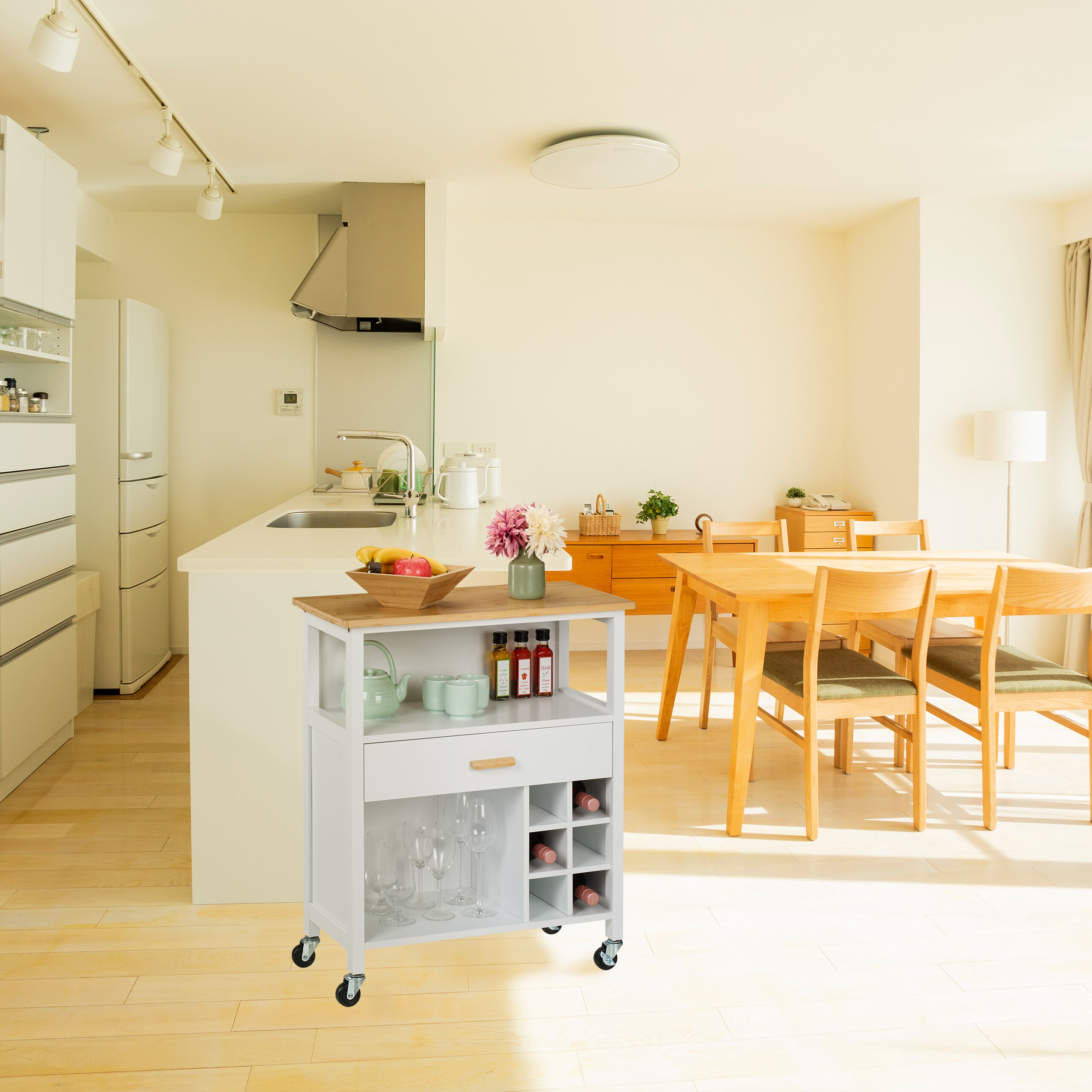 Moderne weiße Küche mit Holzmöbeln, Essbereich und rollbarem Küchenwagen im Vordergrund.