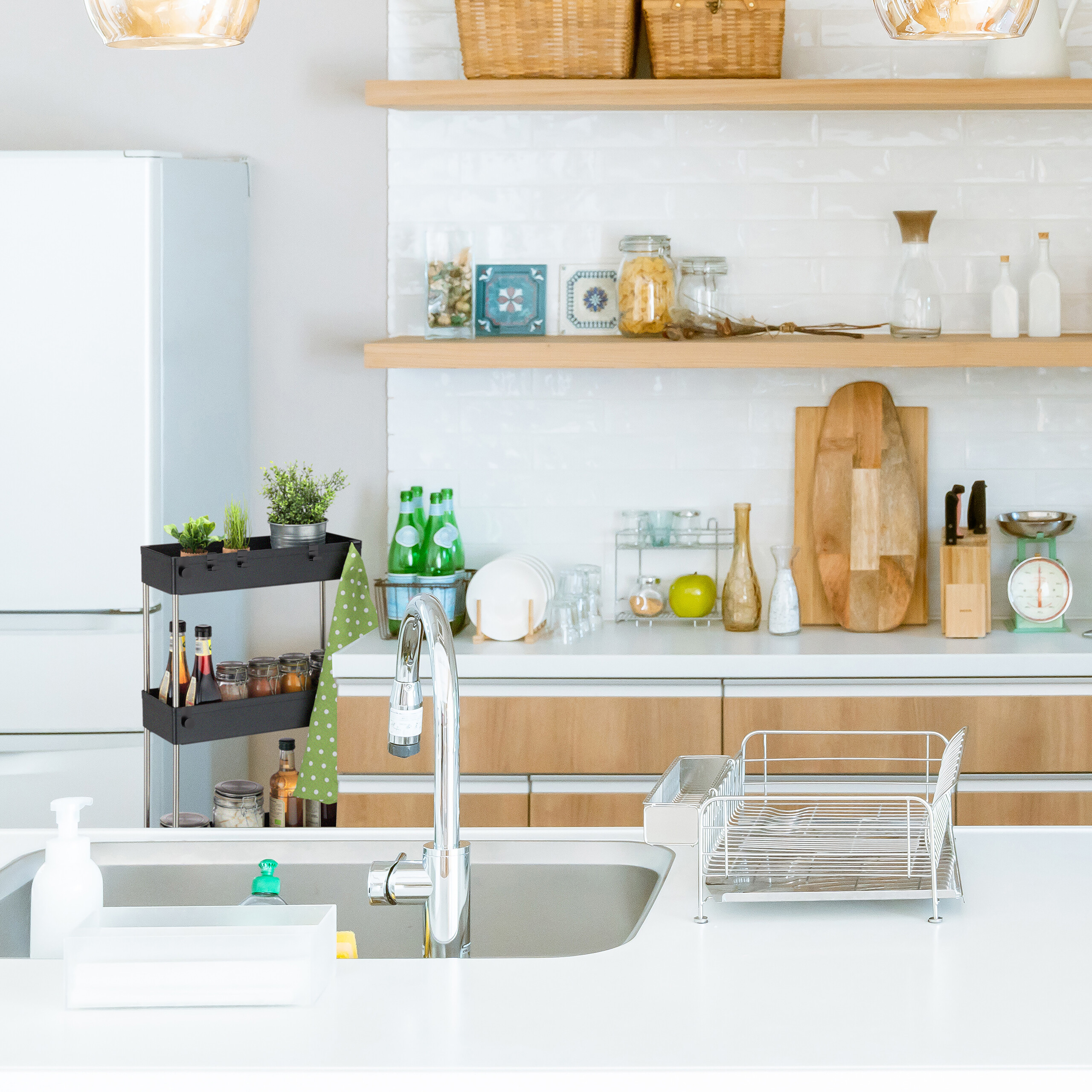 Moderne Küche mit weißer Arbeitsplatte, Edelstahlspüle, Holzböden und offenen Regalen voller Utensilien.