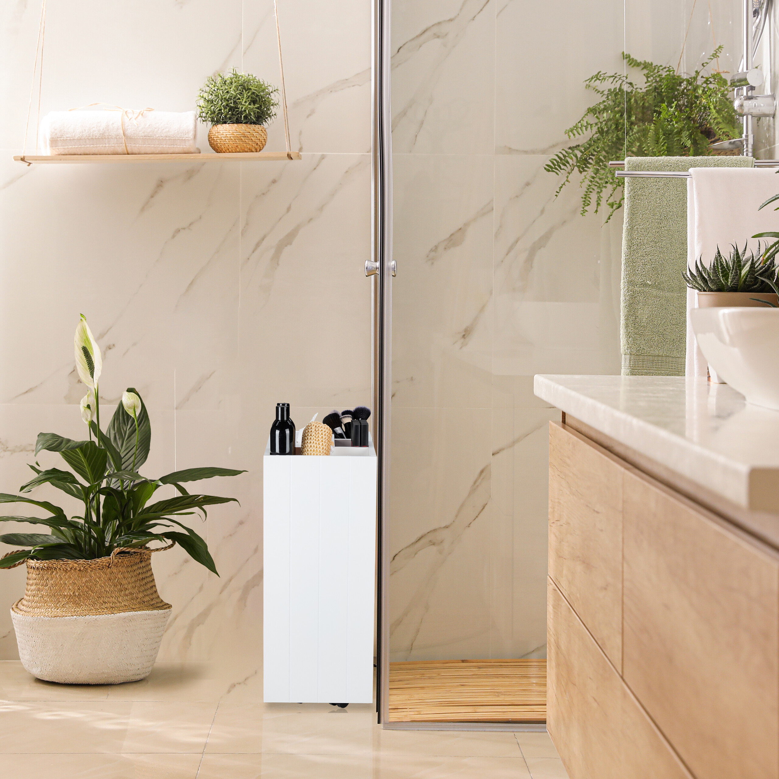 Ein modernes Badezimmer zeigt einen weißen Badschrank neben einer Glasdusche und Pflanzen.