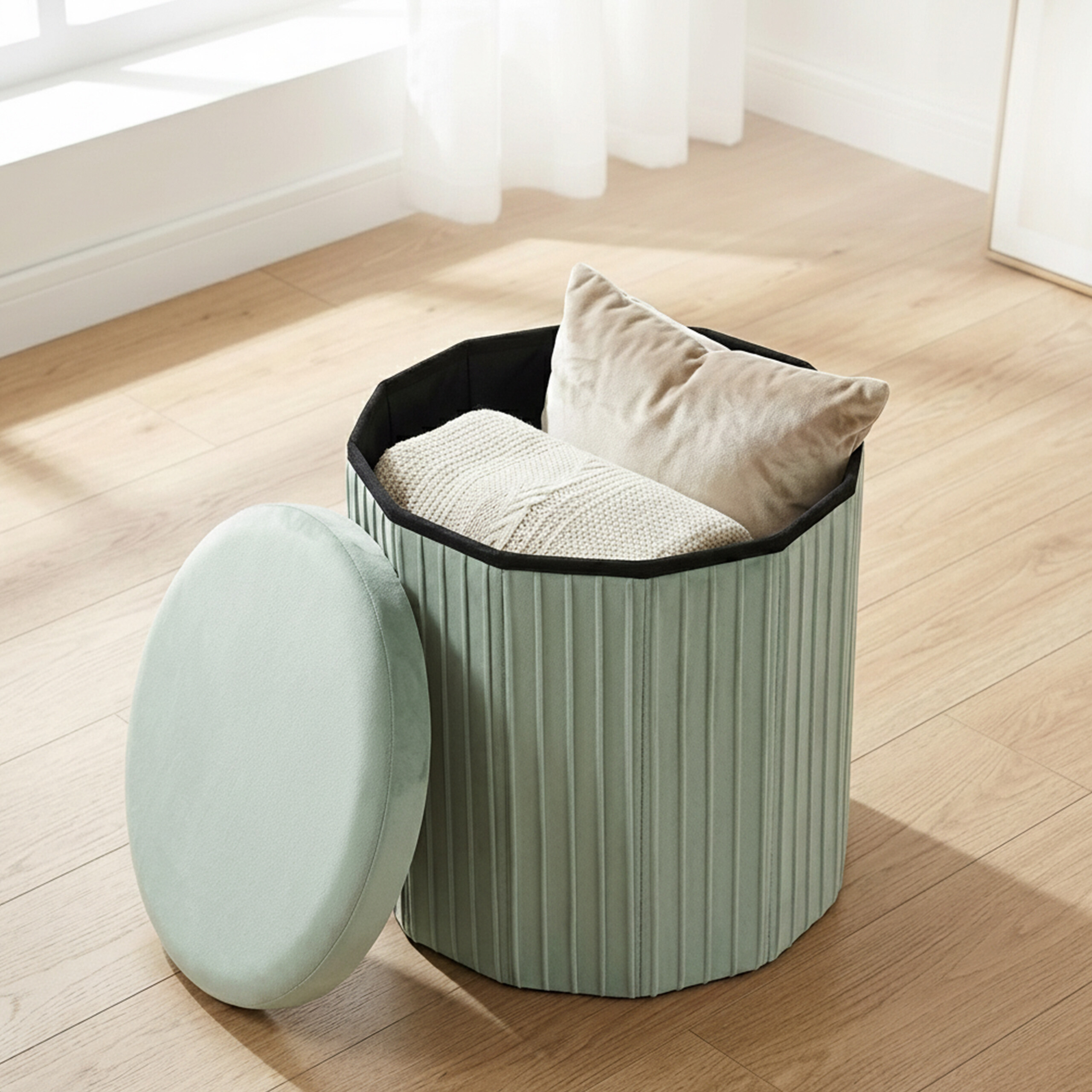 Ein mintgrüner, achteckiger Hocker mit offenem Deckel, gefüllt mit Kissen und Decke auf Holzfußboden.