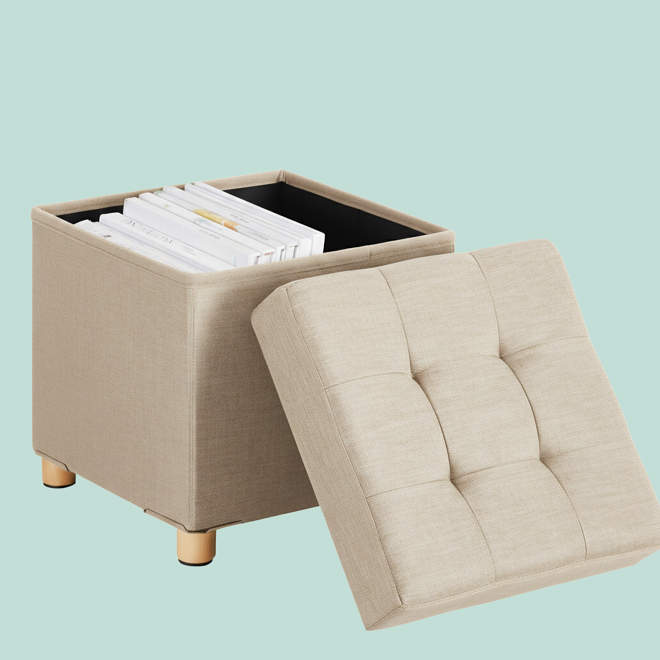 Beige Stoff-Aufbewahrungsbank mit offenem, getuftetem Deckel und Büchern auf hellblauem Hintergrund.