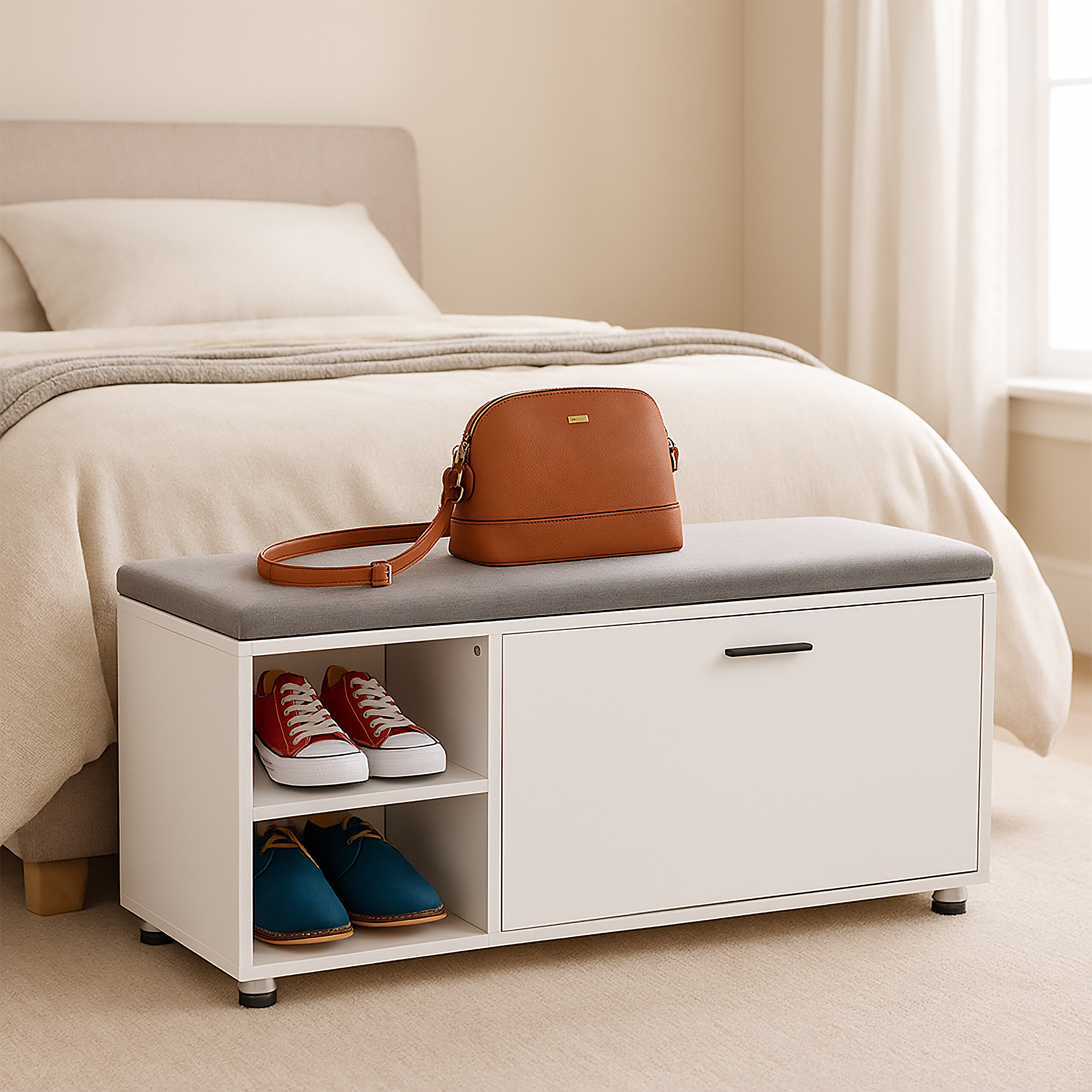 Eine weiße Schuhbank mit grauer Sitzfläche und einer braunen Handtasche steht vor einem Bett im Schlafzimmer.