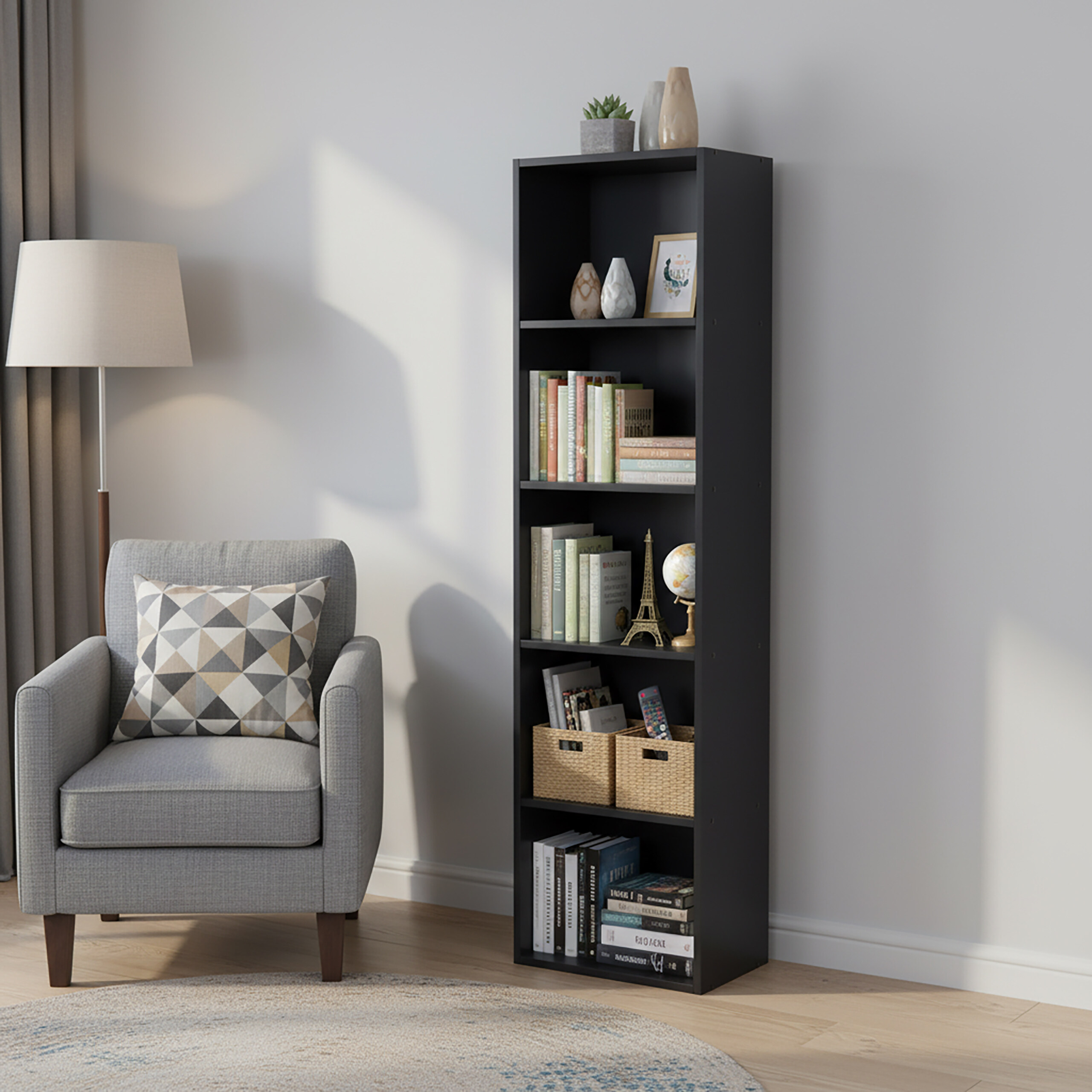 Ein grauer Sessel mit Musterkissen steht neben einem hohen schwarzen Regal mit Büchern, Dekoration und Körben.