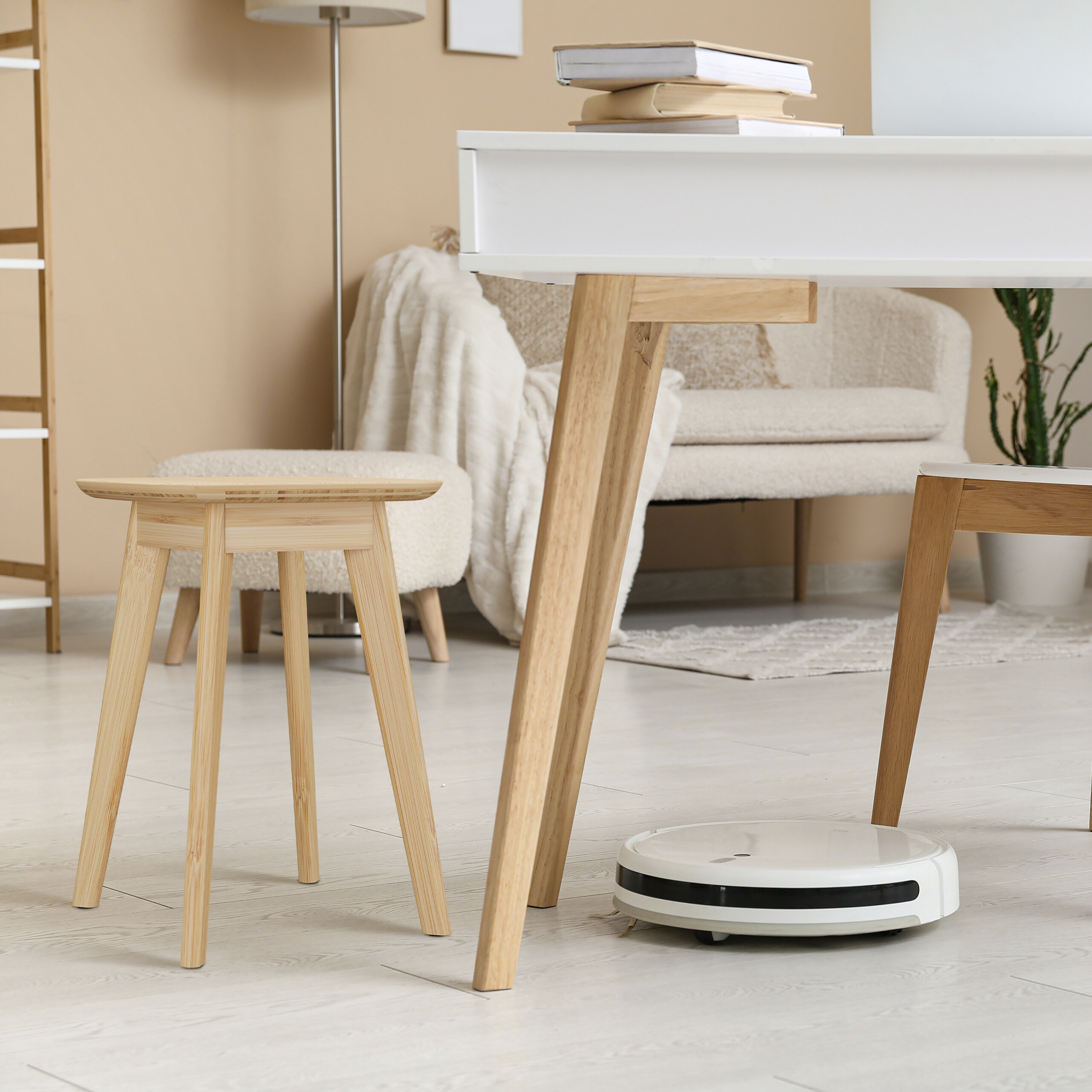 Ein weißer Staubsaugerroboter reinigt den Boden in einem hellen, modern eingerichteten Zimmer.