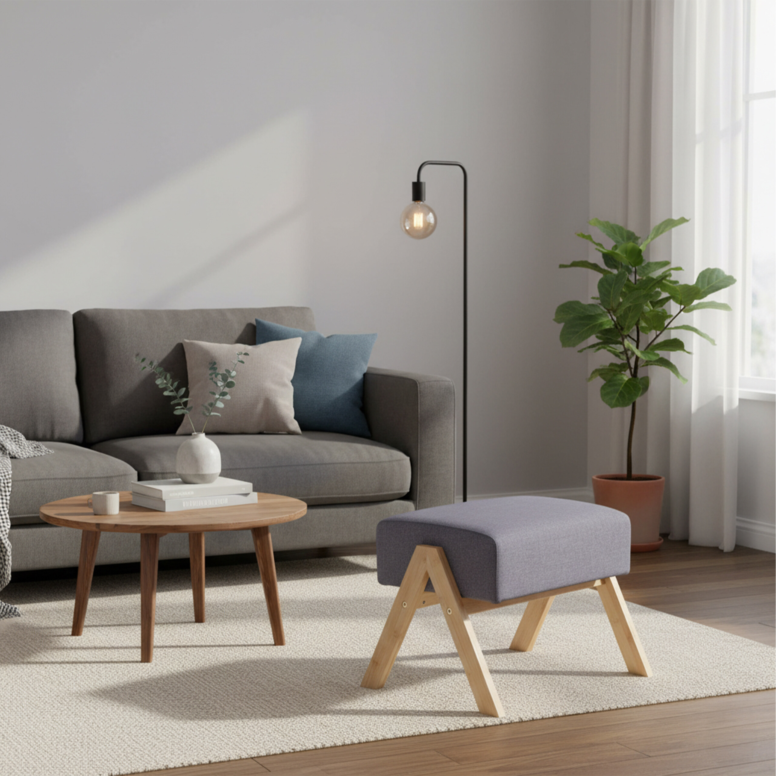 Gemütliches Wohnzimmer mit grauem Sofa, Holztisch, Lampe, Pflanze und Hocker auf hellem Teppich.