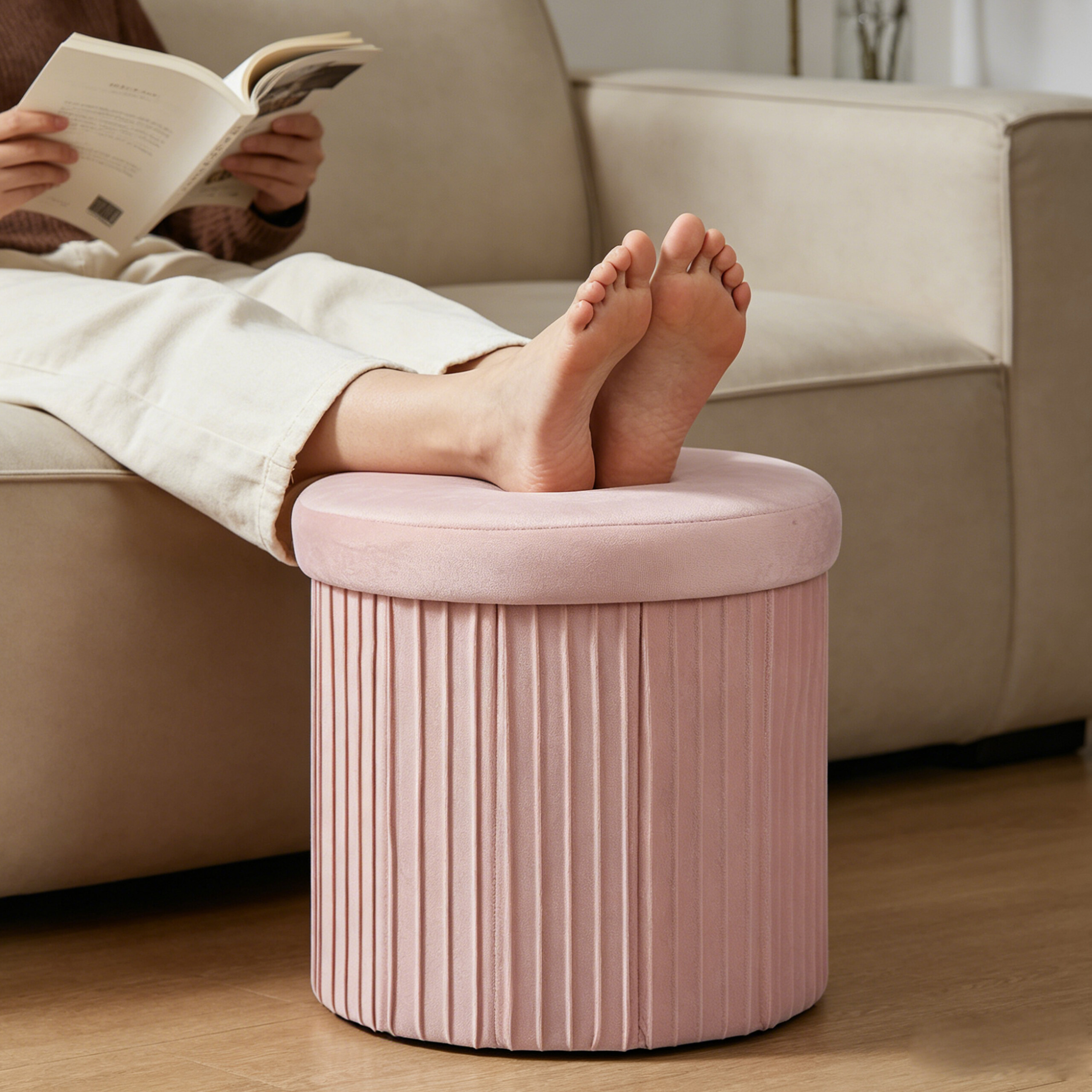 Eine Person entspannt auf einem Sofa, die nackten Füße ruhen auf einem rosa gepolsterten Hocker.