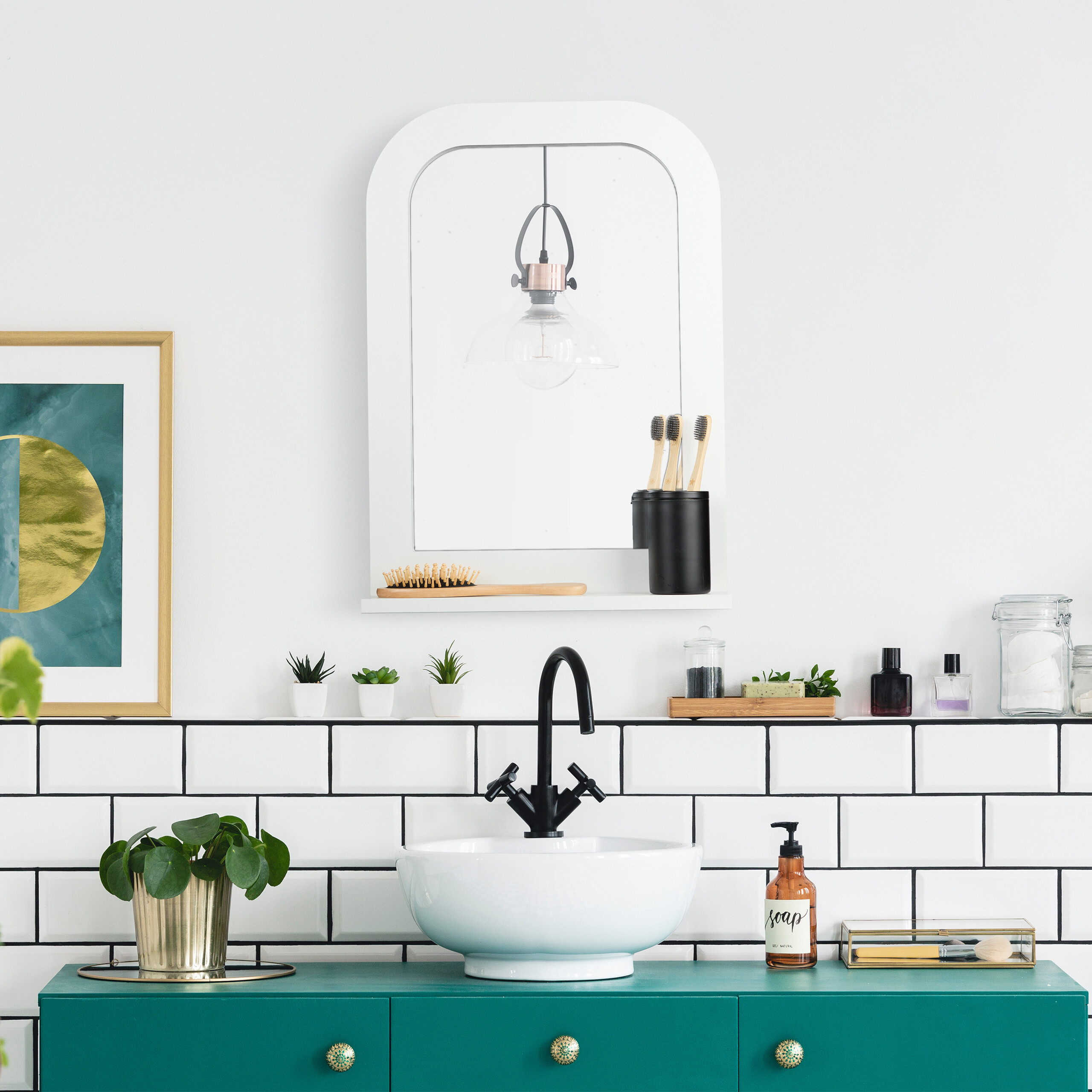 Badezimmer mit weißer Wand, grünem Waschtisch, weißem Waschbecken und Spiegel mit Hängeleuchte.