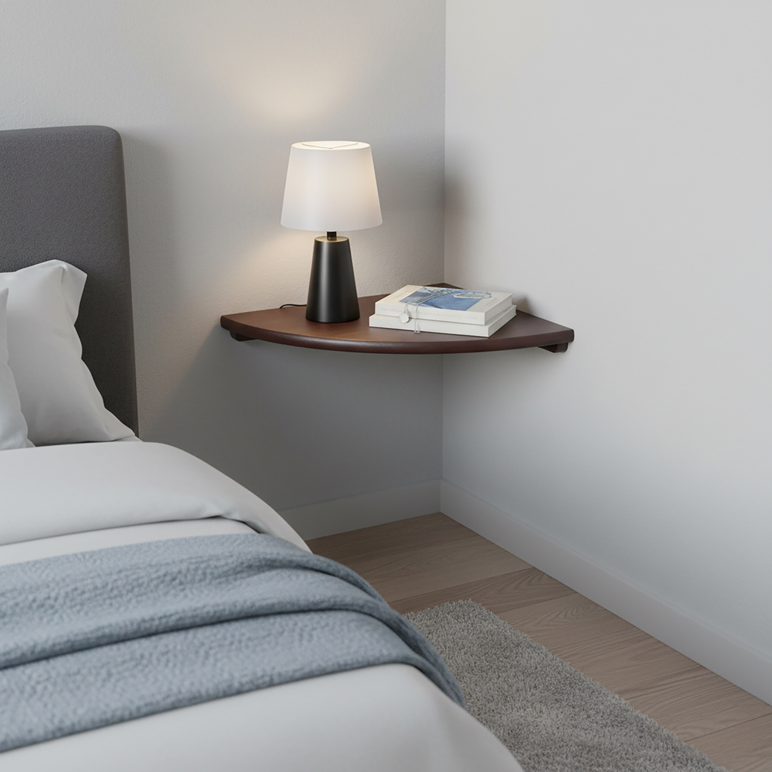 Eine eckige Nachtschale aus Holz an der Wand mit einer Lampe und Büchern neben einem grauen Bett.