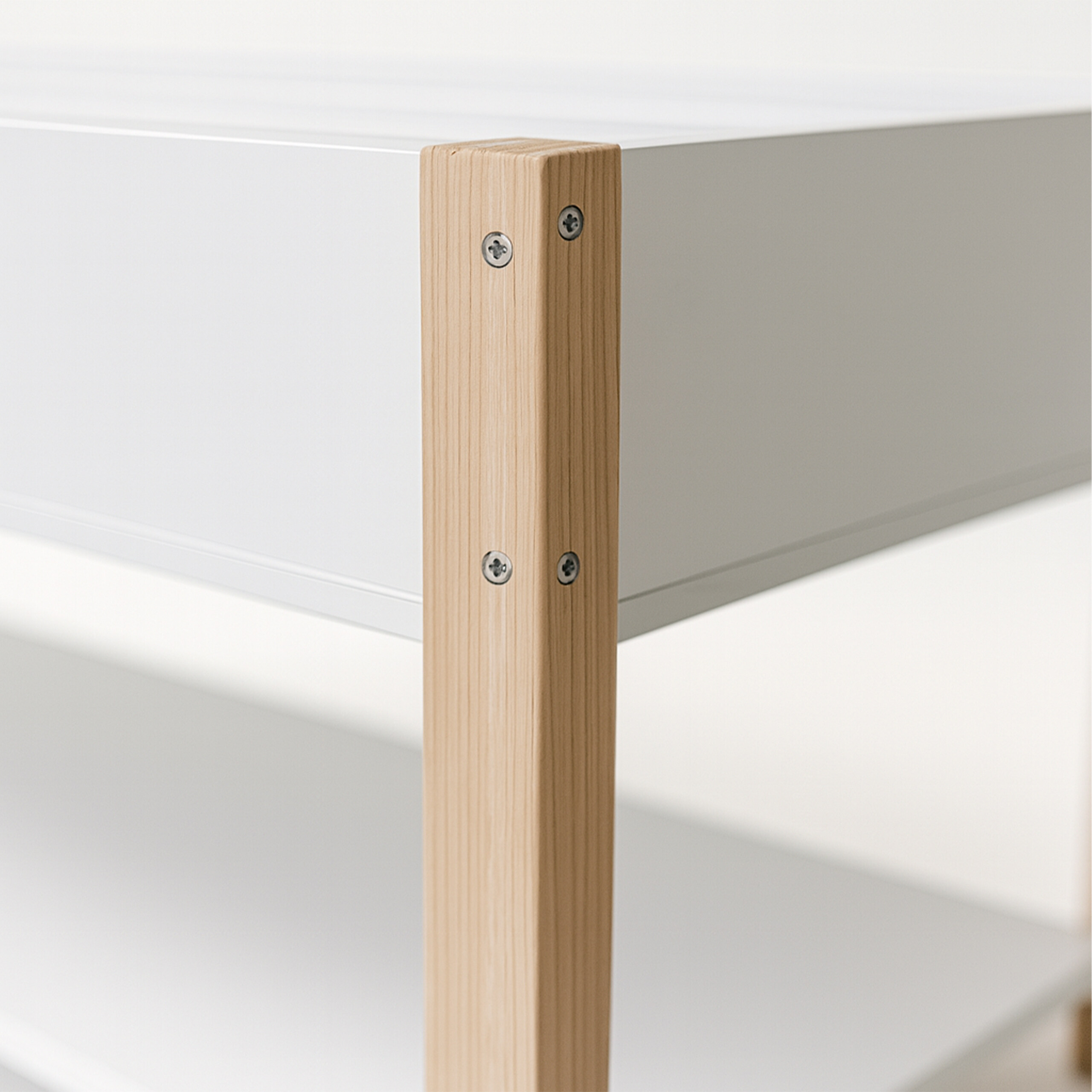 Nahaufnahme einer Holzecke eines weißen Möbels mit sichtbaren Schrauben.