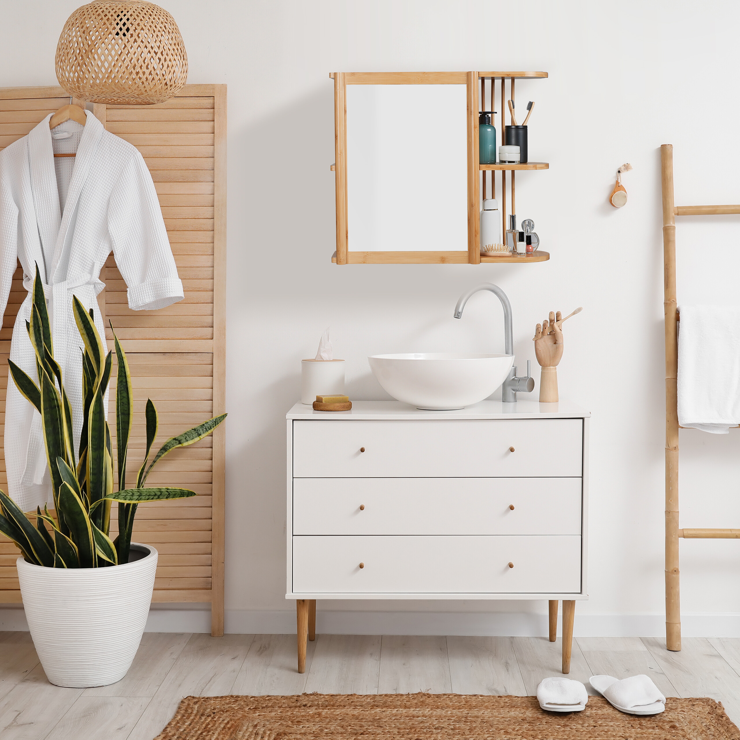 Ein modernes weißes Badezimmermöbel mit Waschbecken, Spiegelschrank und Pflanze vor heller Wand.
