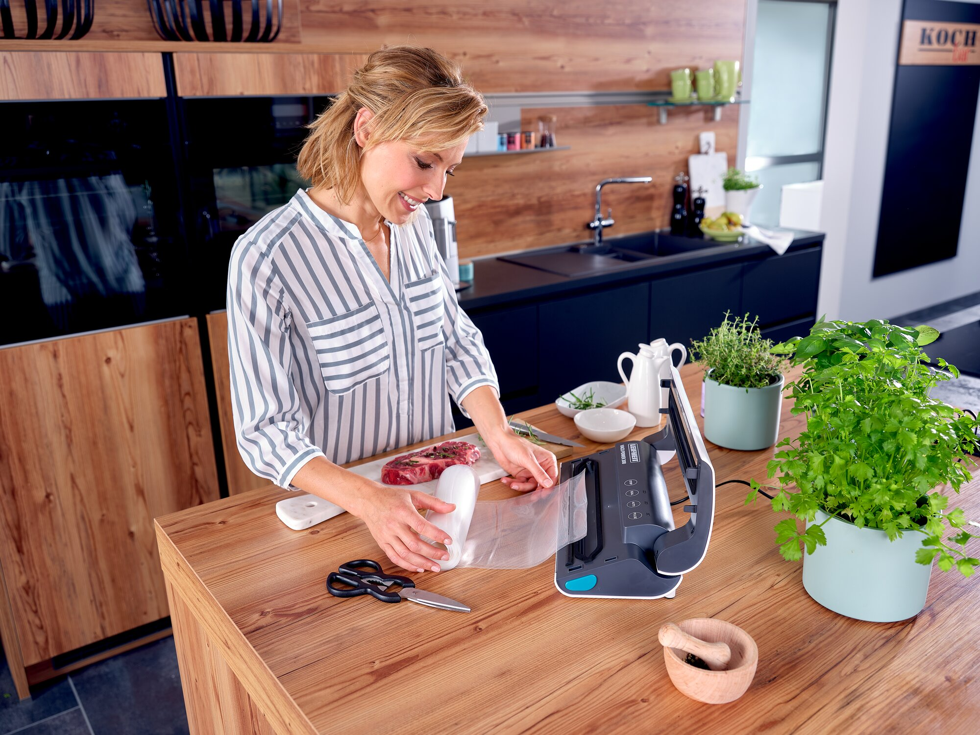 Una mujer en una cocina moderna usa una envasadora al vacío para carne.