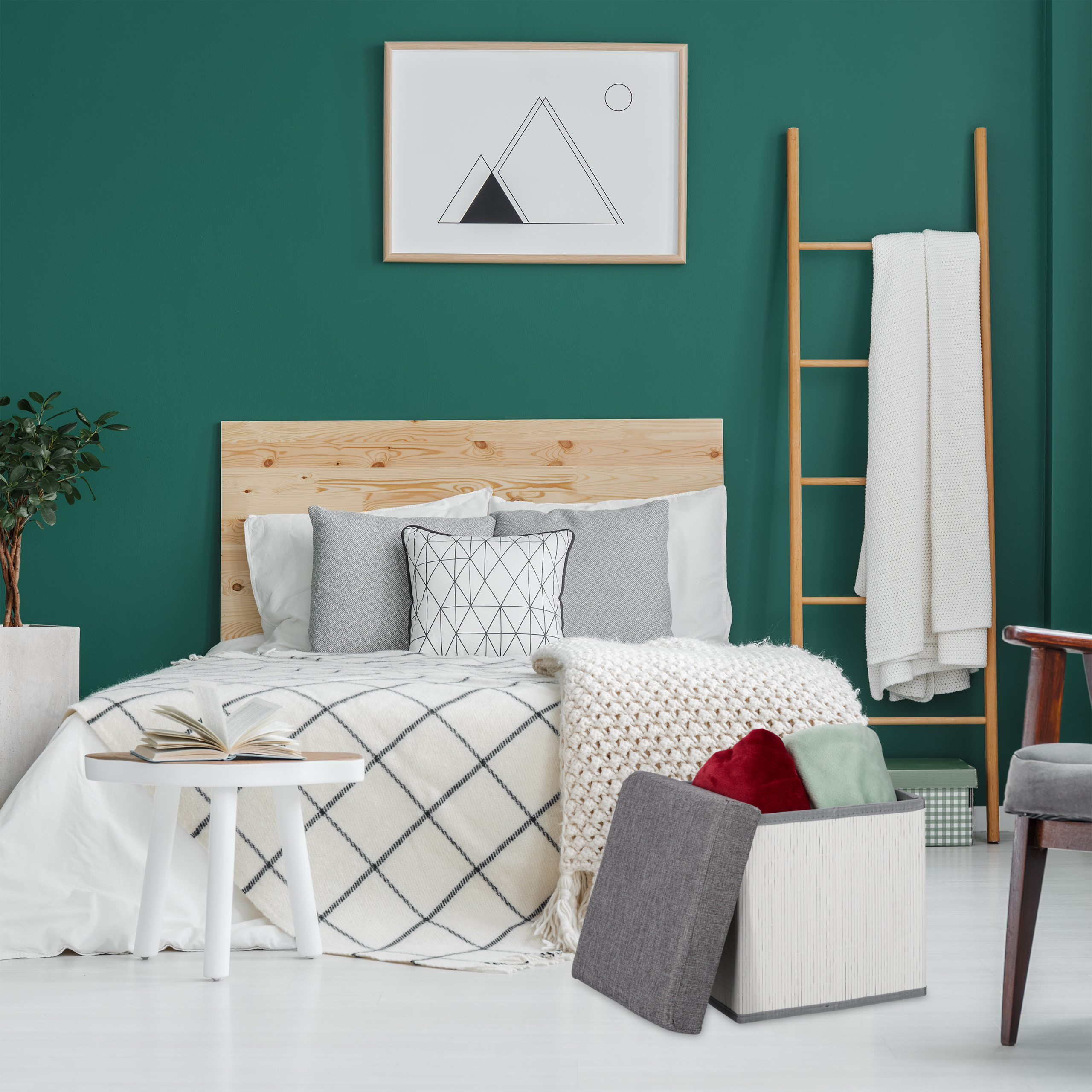 Ein gemütliches Schlafzimmer mit grünen Wänden, Holzbett, weißer Bettwäsche, eingerahmter Kunst und Holzleiter.