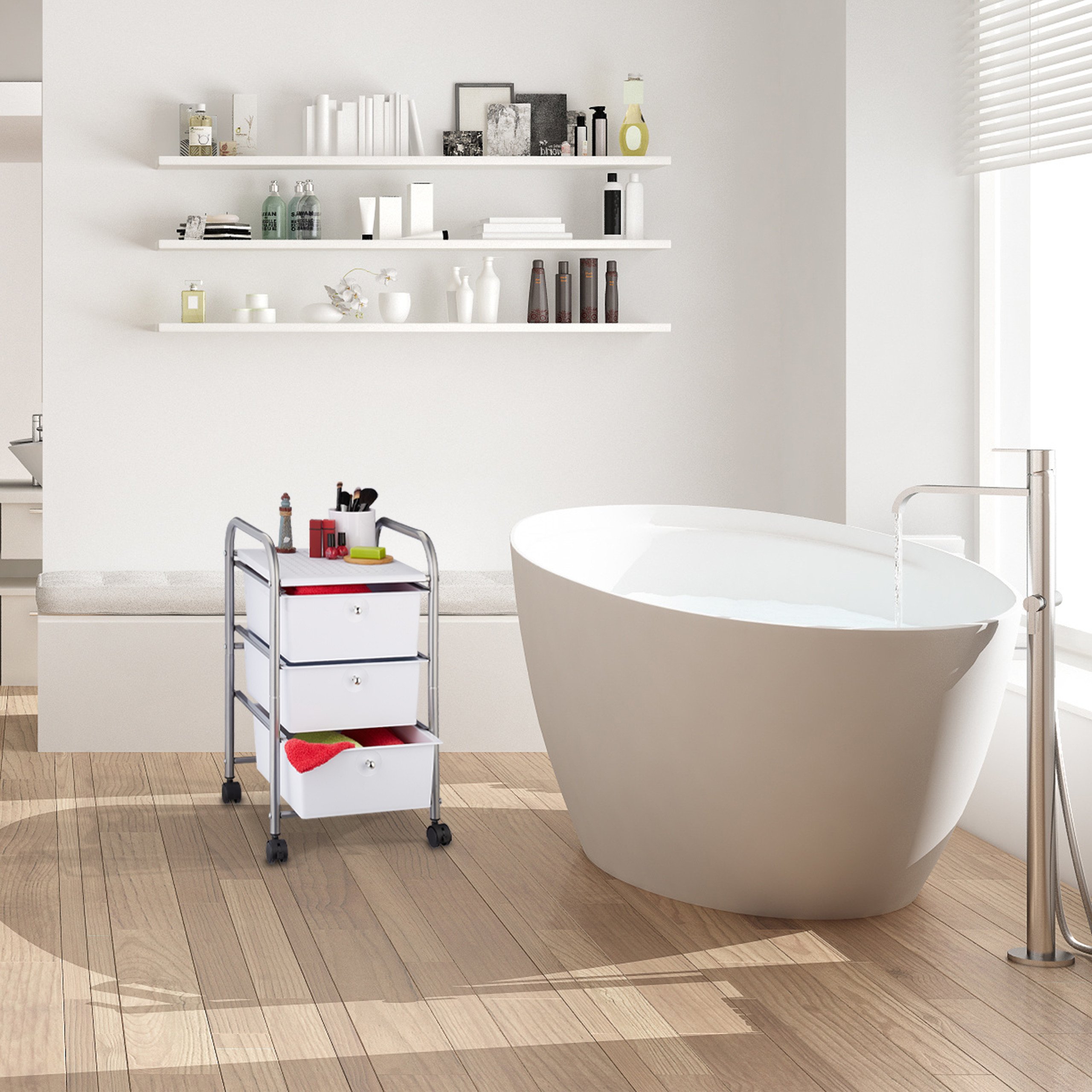 Moderne weiße Badewanne, ein dreistufiger Badewagen auf Rädern und drei Regale voller Kosmetik an einer weißen Wand.