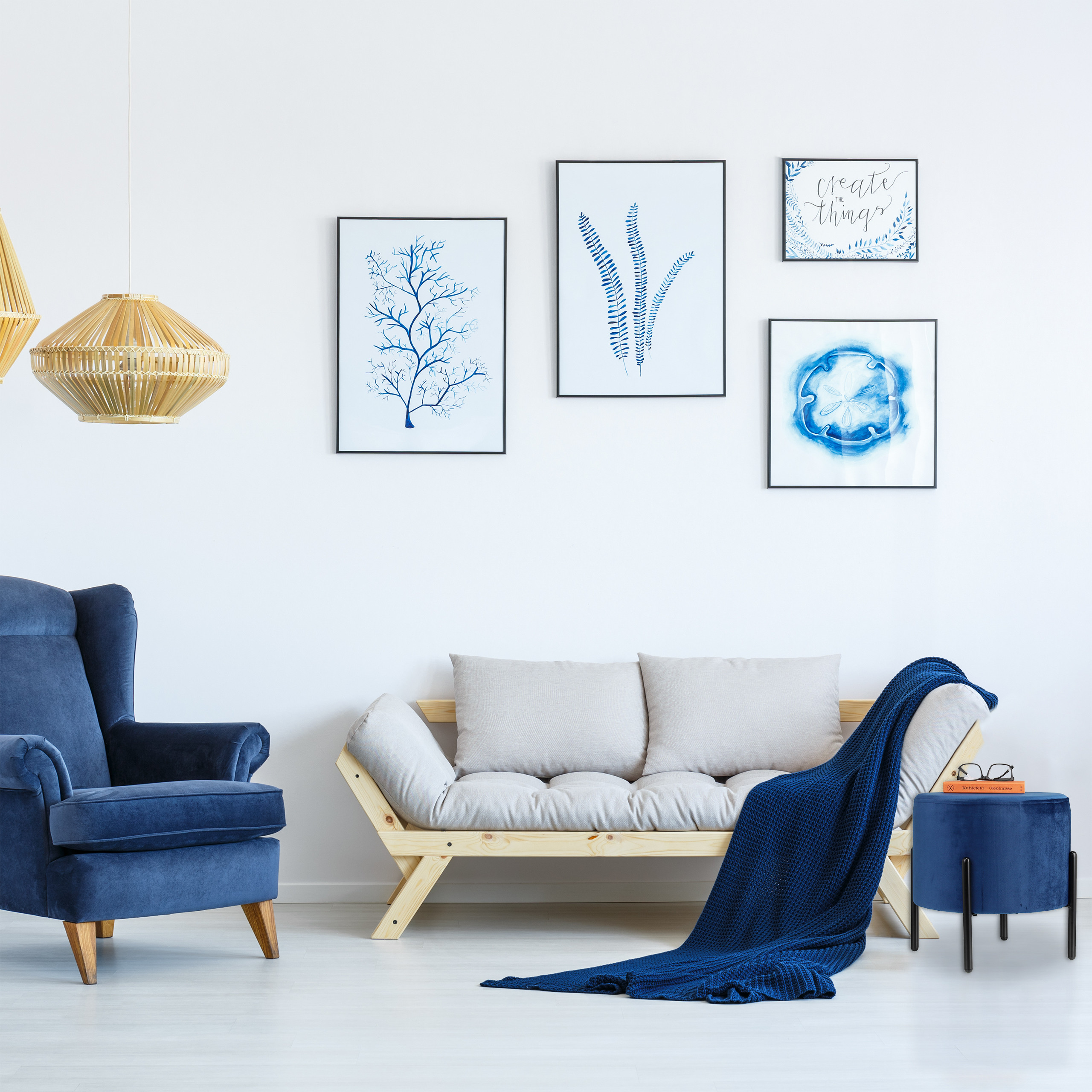 Ein weißes Wohnzimmer mit blauem Sessel, Holzsoufa, blauer Decke und blauen Wandkunstwerken.