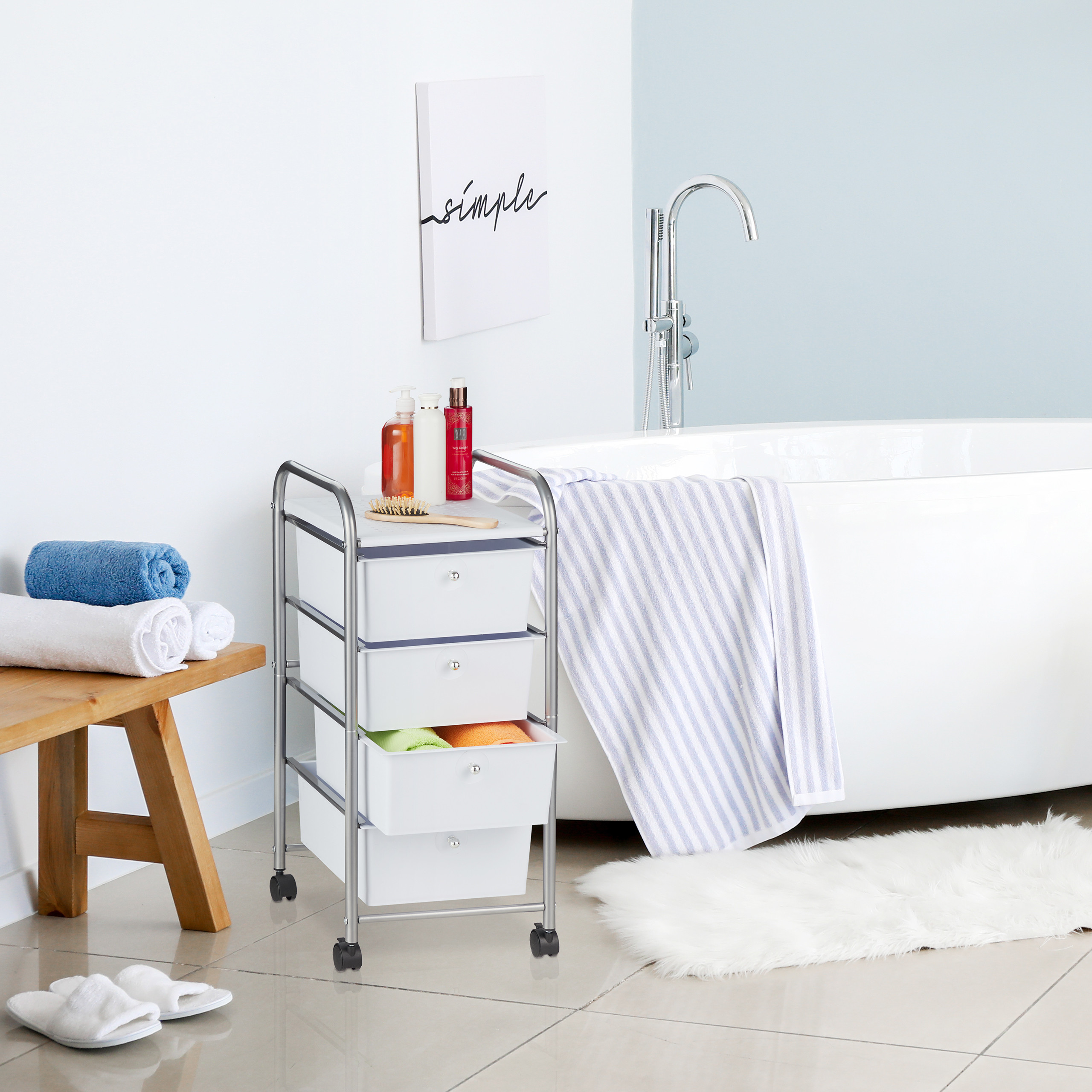 Ein weißer Schubladenwagen mit Utensilien steht in einem modernen Badezimmer neben einer Badewanne.