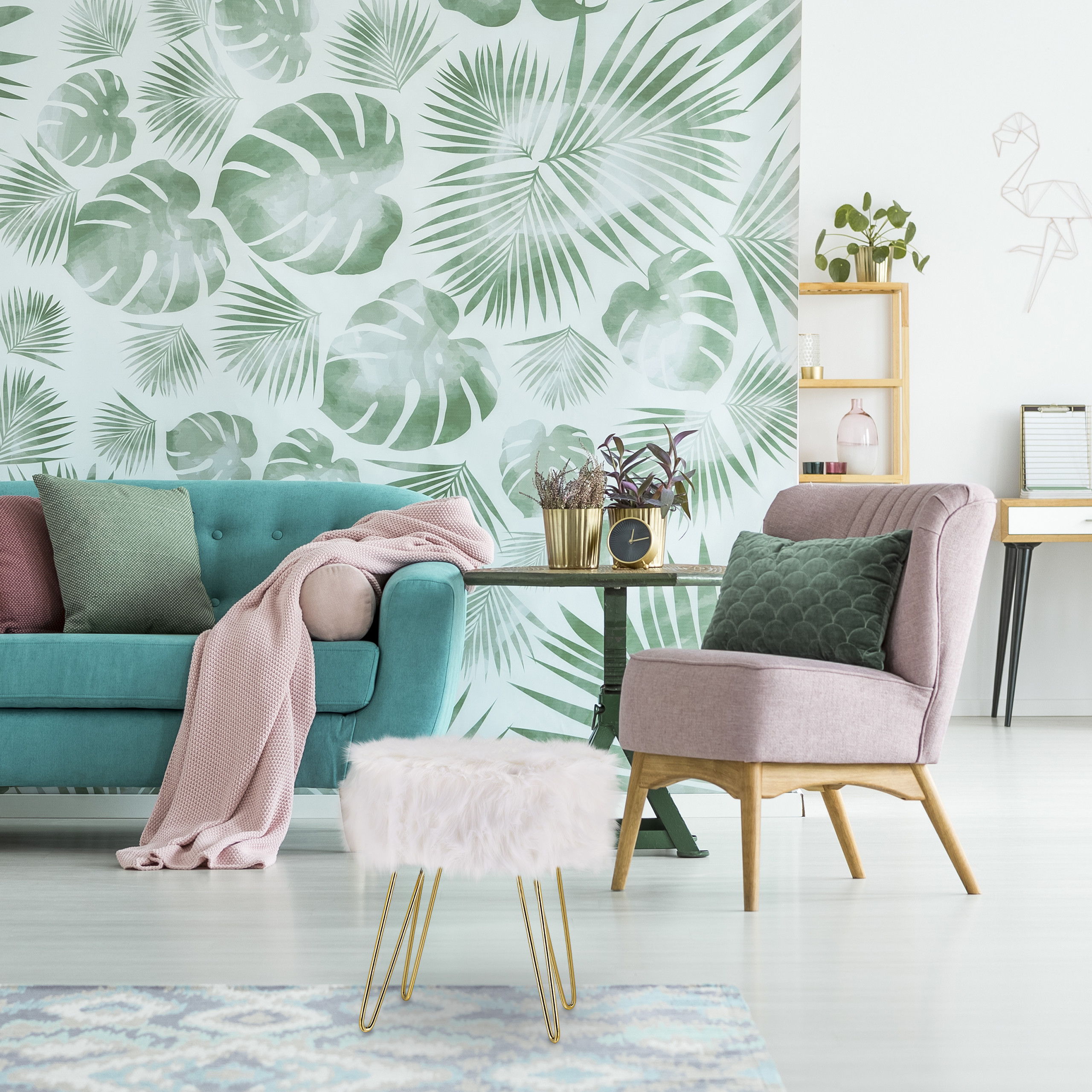 Wohnzimmer mit blauem Sofa, rosa Sessel, Pelzhocker und Wand mit tropischem Blättermotiv.