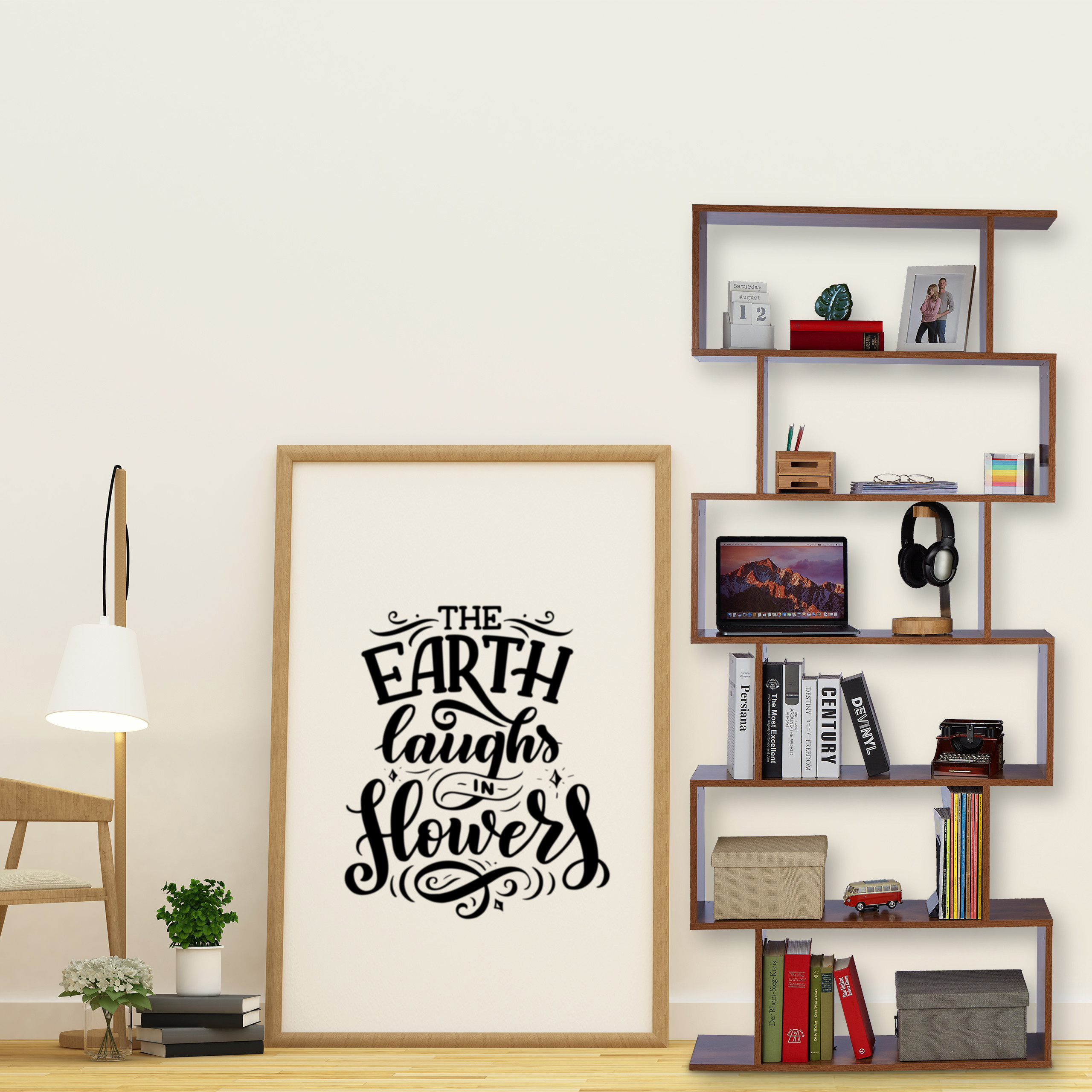 Ein hölzernes Regal mit Büchern, Laptop und Dekoration, neben einem großen gerahmten Plakat und Stehlampe.