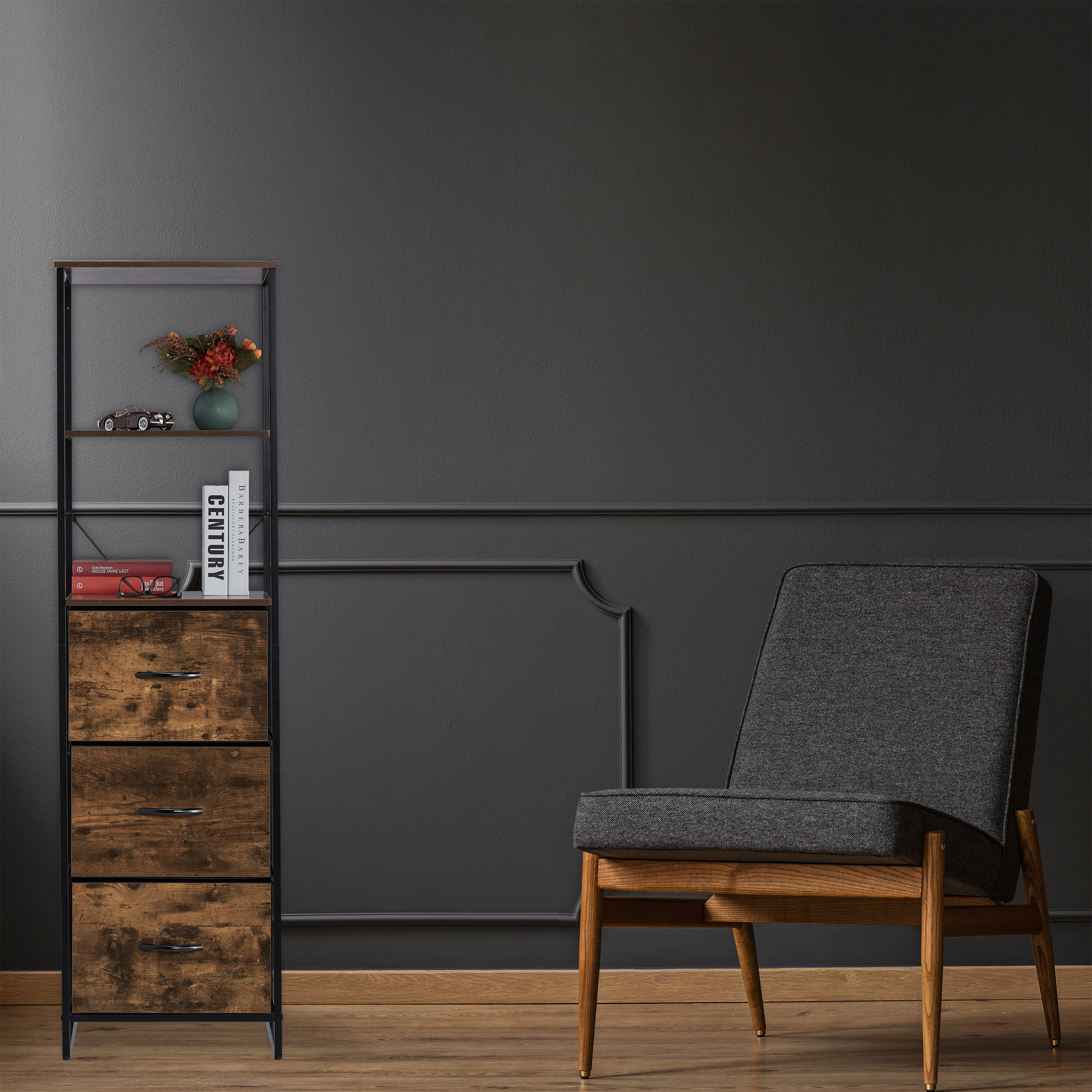 Ein grauer Sessel steht vor einer dunkelgrauen Wand neben einem Regal mit Blumen und Büchern.