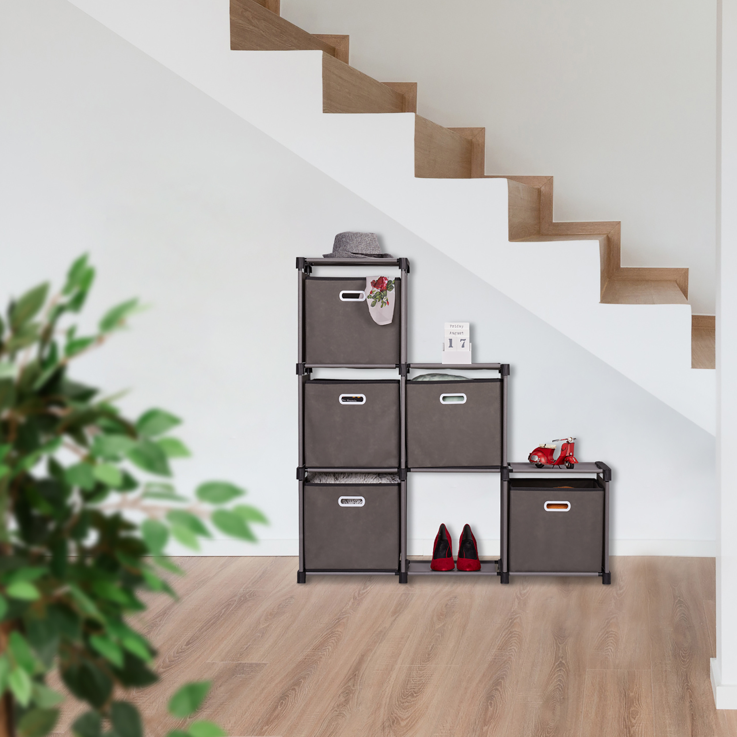 Modulares graues Stoffregal unter einer Treppe mit Dekor, roten Schuhen und einer unscharfen Pflanze im Vordergrund.